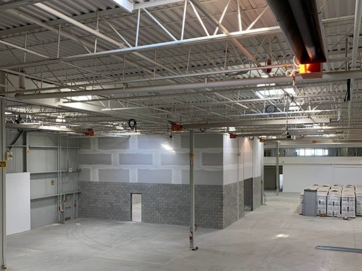 Interior of a building under construction. Walls are partially constructed, with exposed ceiling beams and concrete floor.