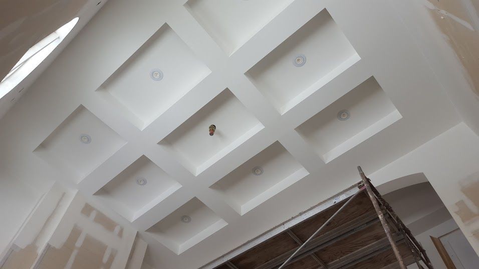 White coffered ceiling with recessed squares, possibly under construction, scaffolding visible.