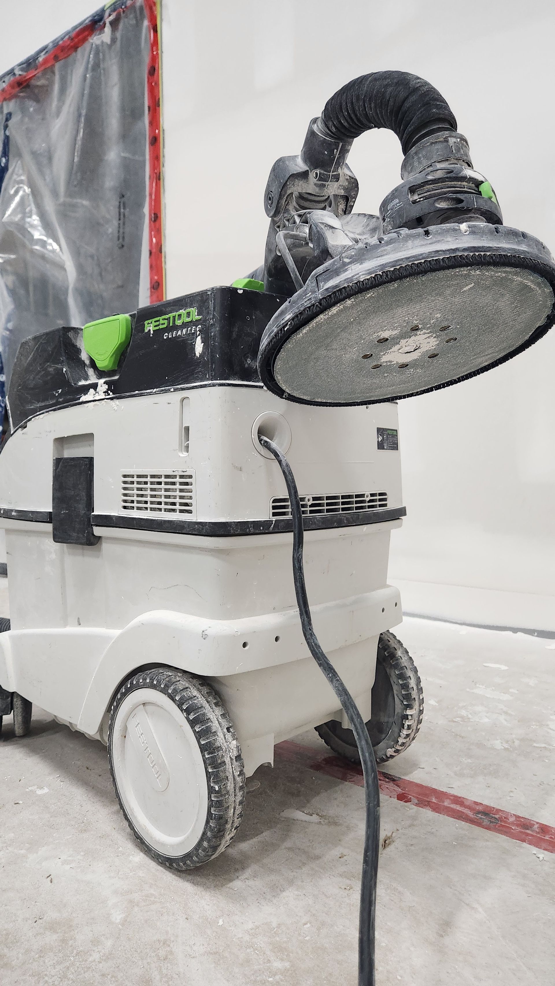 A vacuum cleaner is sitting on the floor next to a wall.