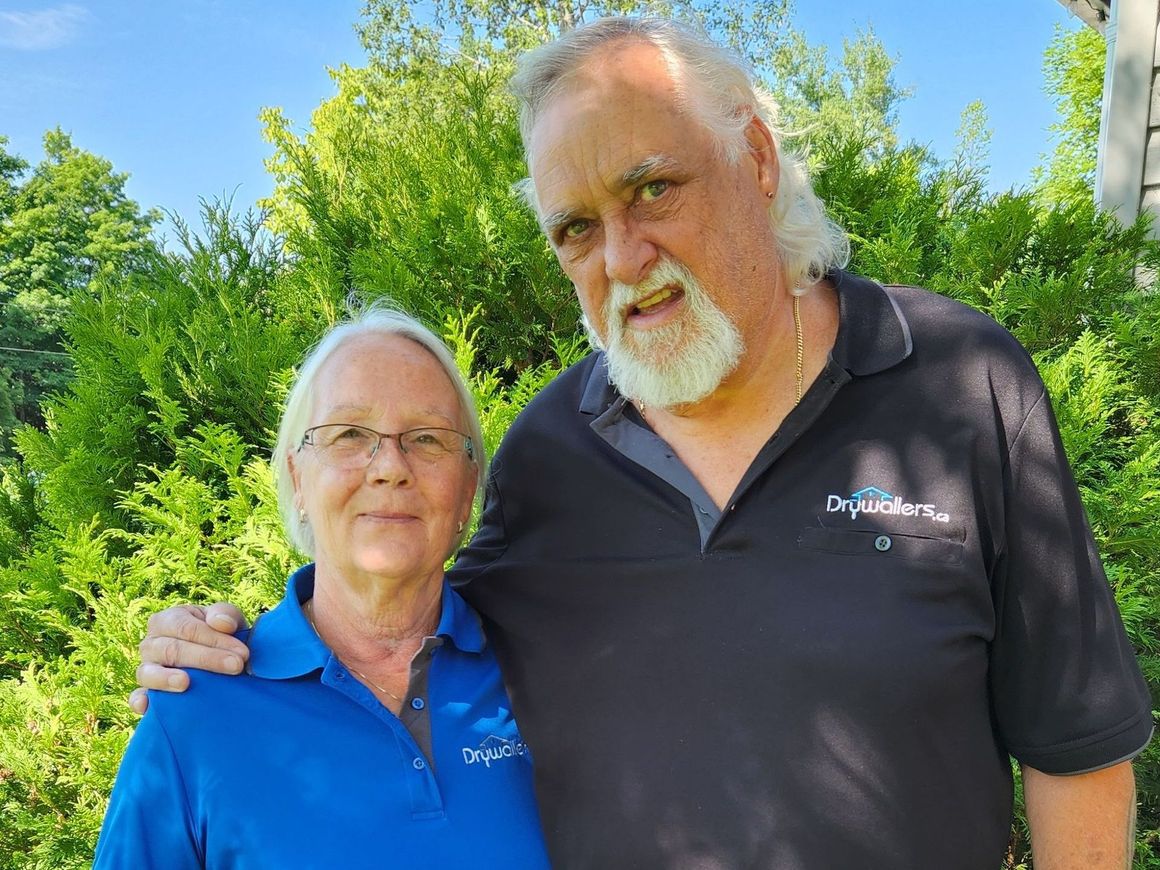 A man and a woman are posing for a picture in front of trees.