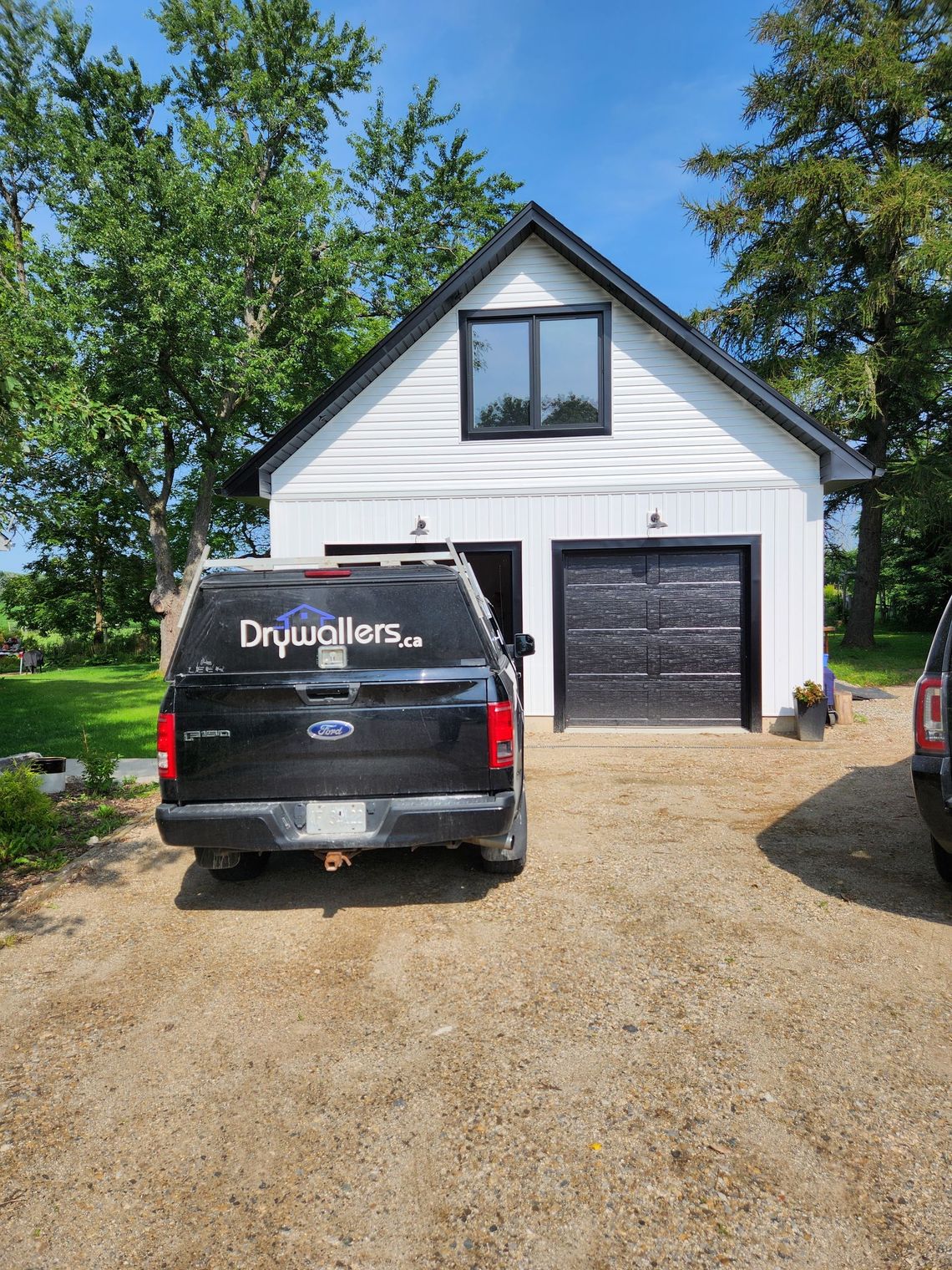 A black suv is parked in front of a white garage.