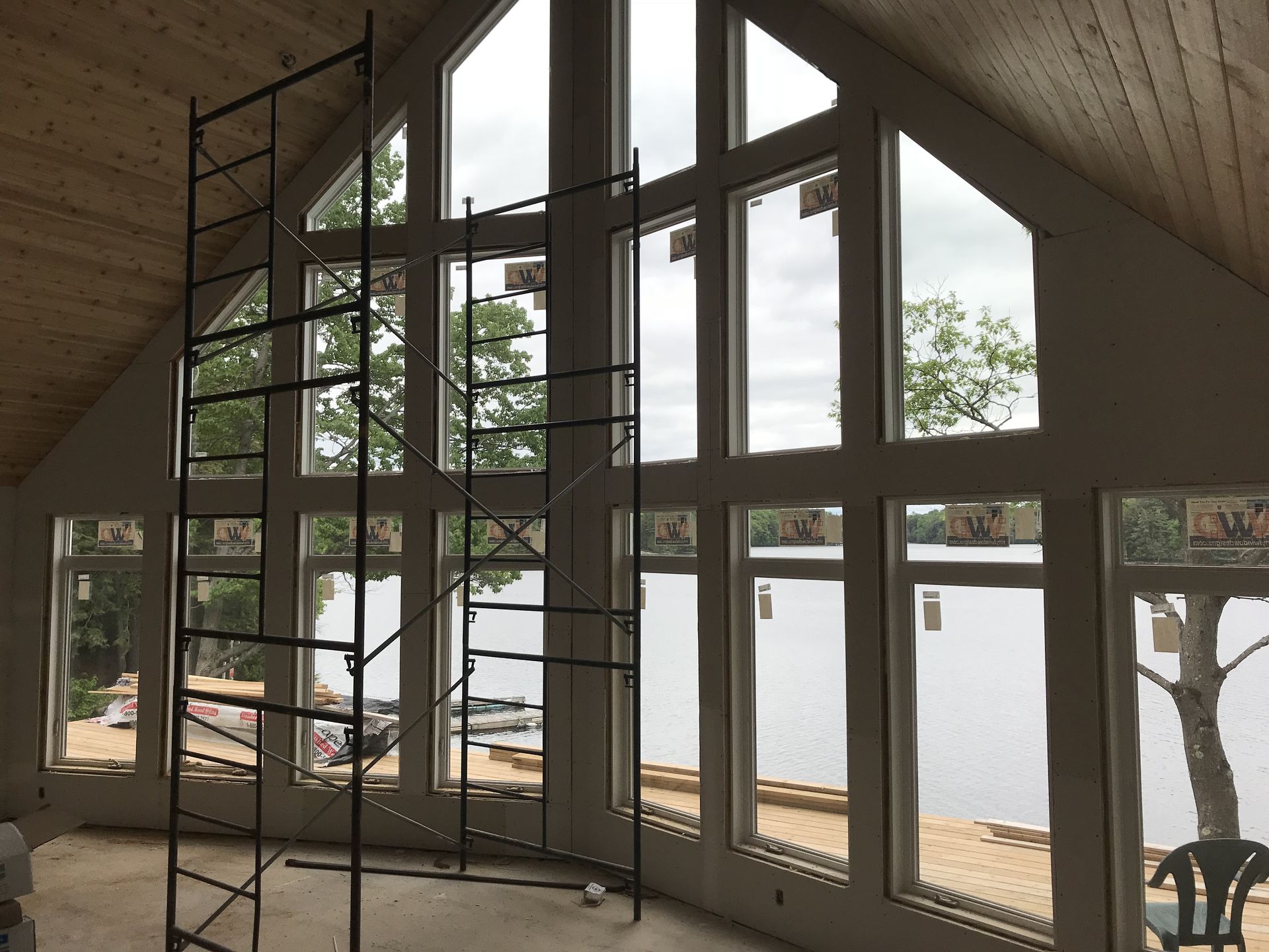 Interior with large windows overlooking water, scaffolding in front. Building under construction.