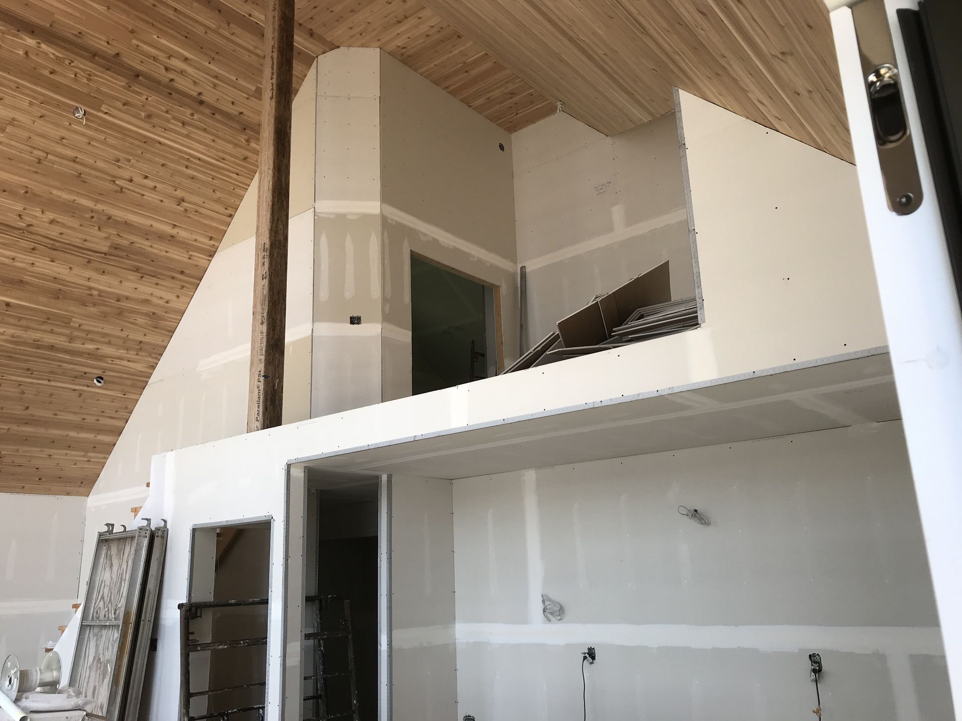 Interior under construction, featuring drywall, unfinished beams, and a loft area.