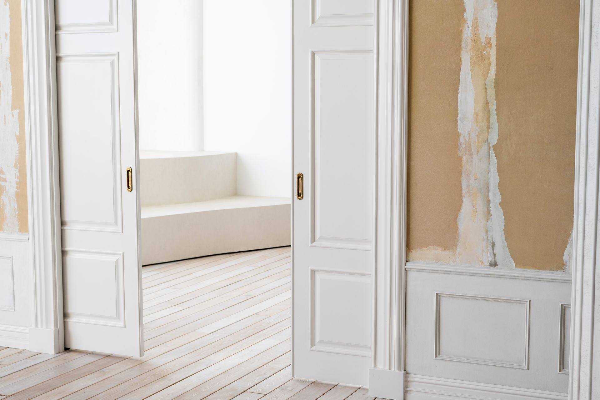 White sliding doors open to a bright room with a built-in bench. Wooden floor.