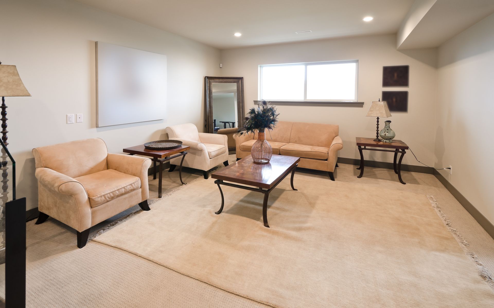 Living room with beige furniture, patterned rug, and large mirror.