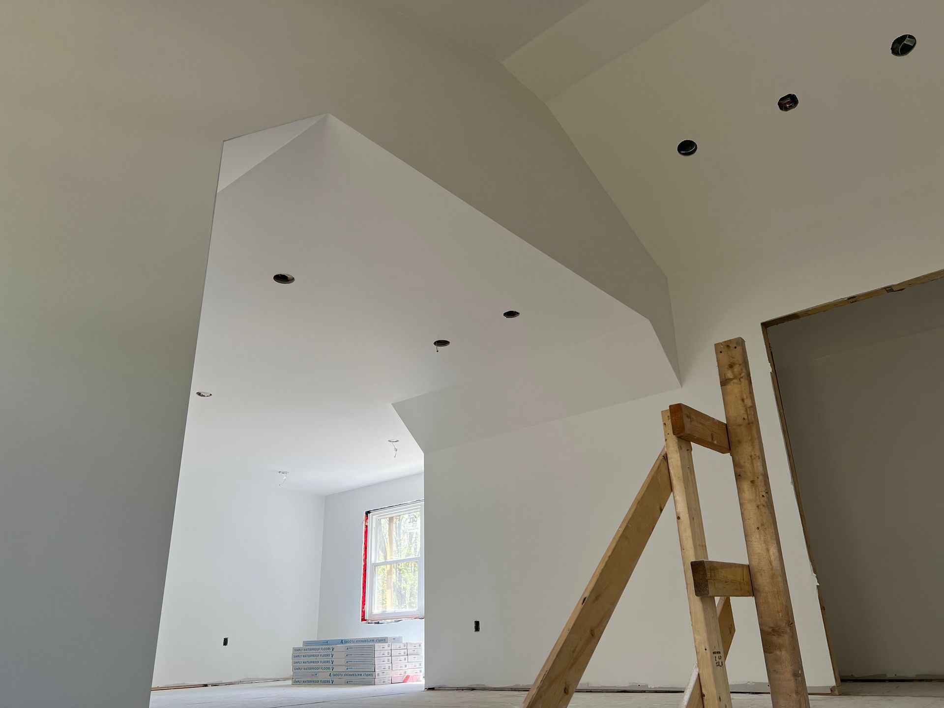 A wooden ladder is sitting in a room with white walls.