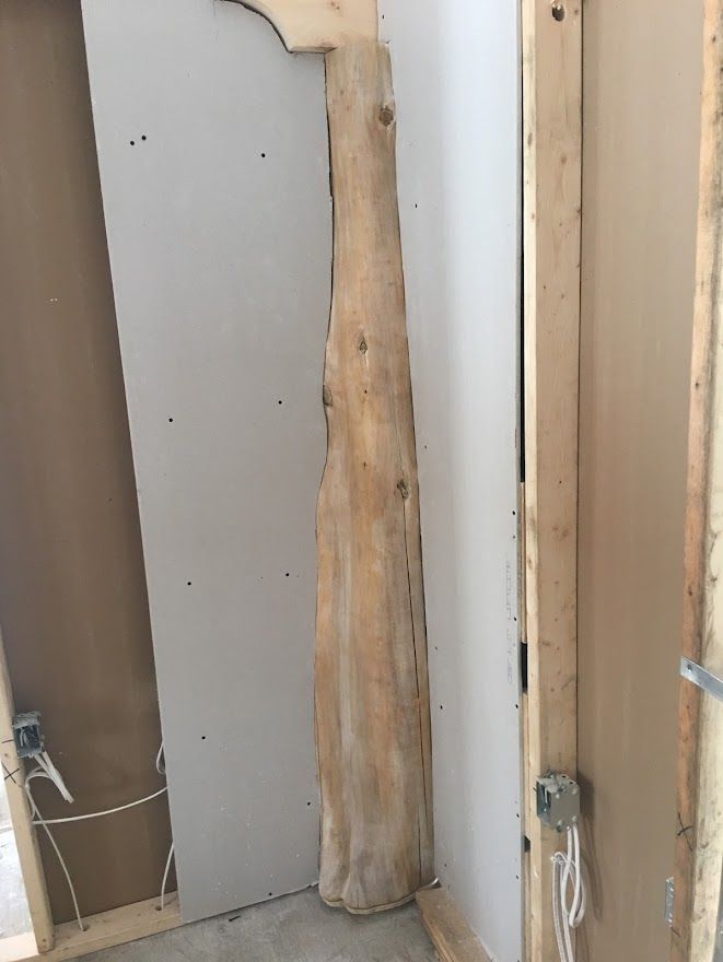 Wooden support beam against drywall in a construction site.