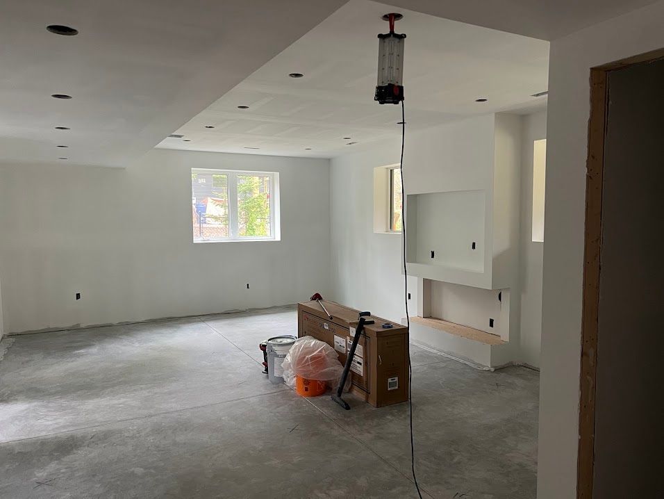 A large empty room with white walls and a concrete floor.