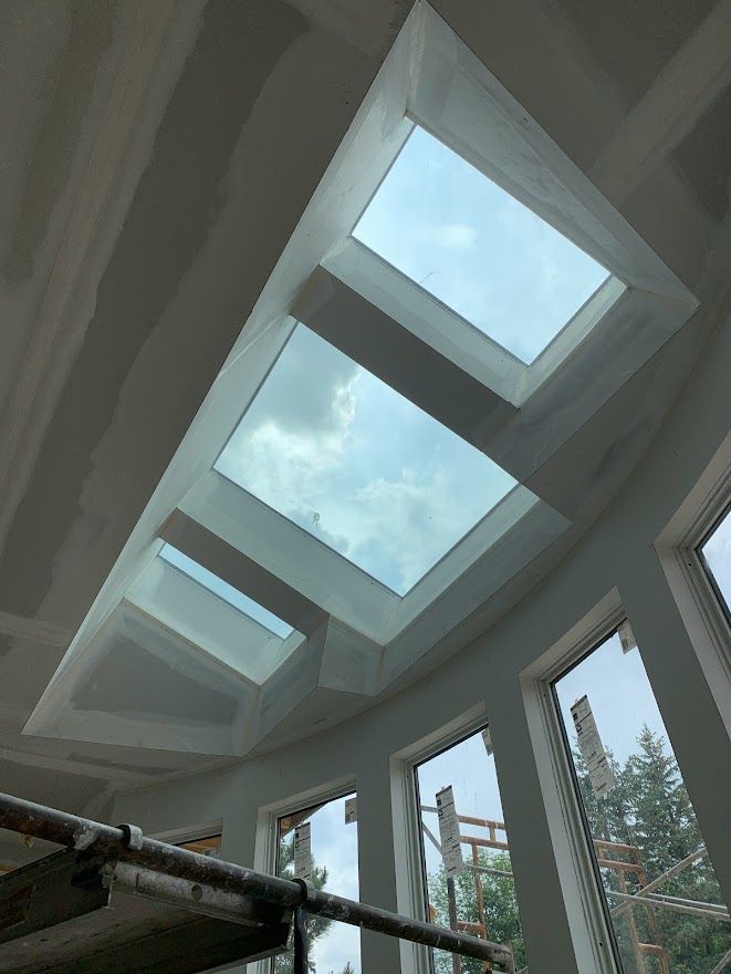 Skylights in a ceiling under construction; cloudy sky visible through the glass.