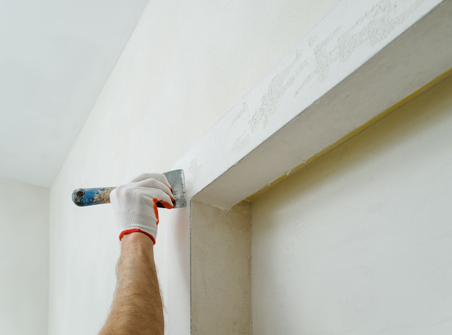 A man is plastering a wall with a spatula.