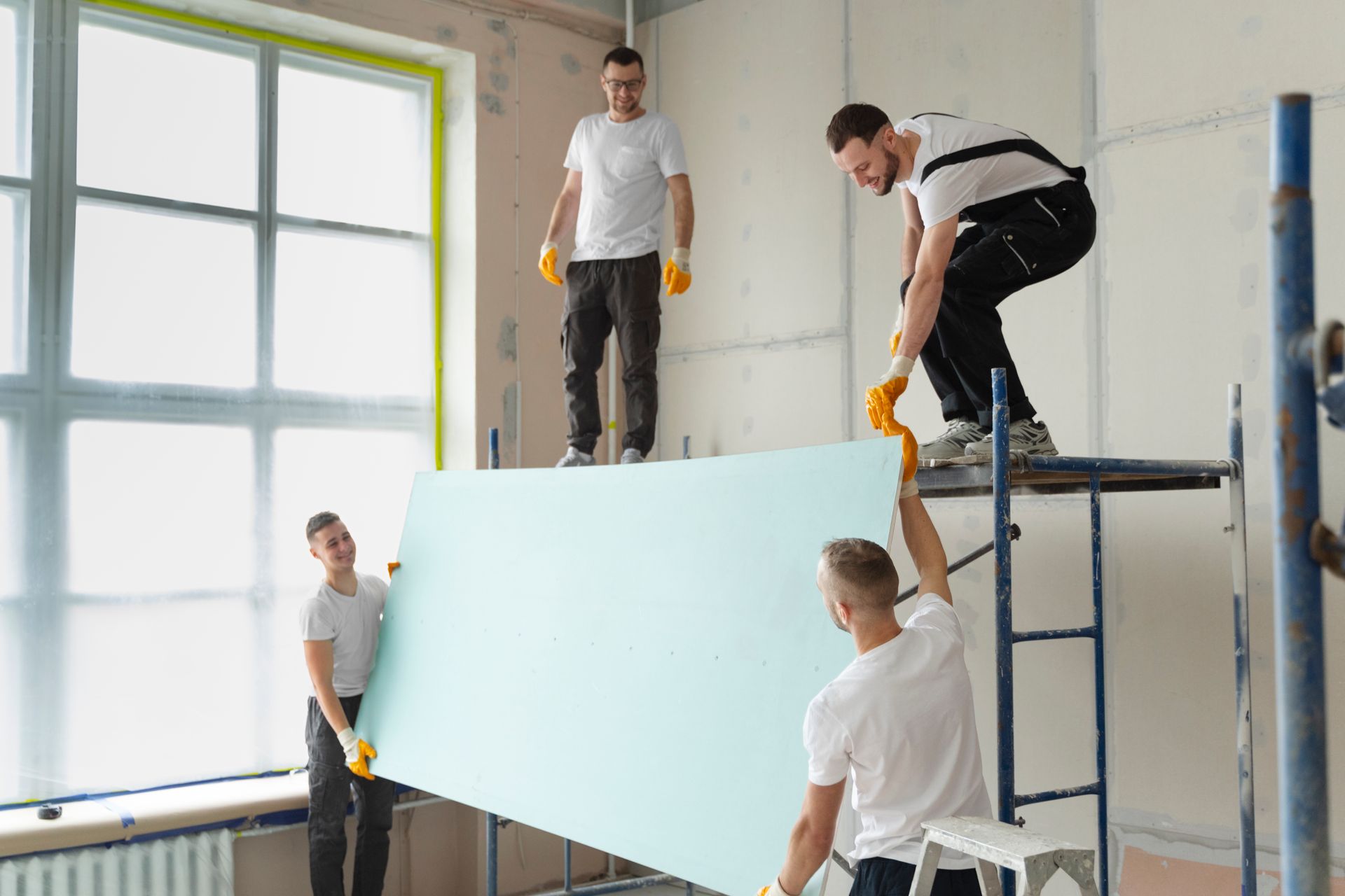 A group of men are working on a wall in a room.