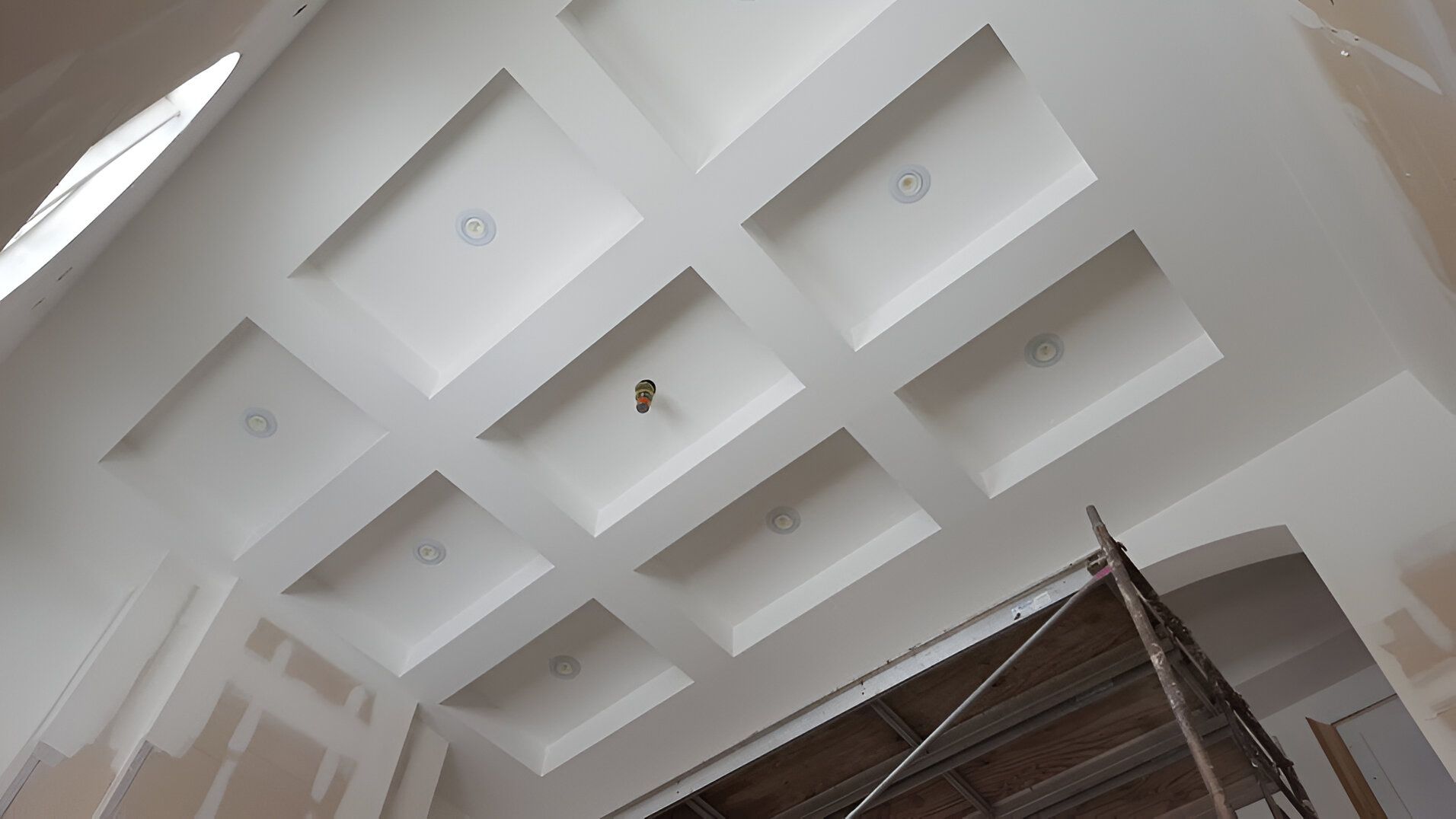 A ceiling with a lot of squares on it and a scaffolding in the background.