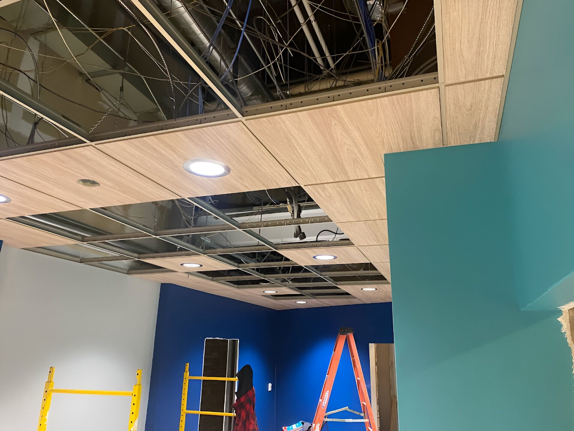 A man is standing on a ladder in a room under construction.