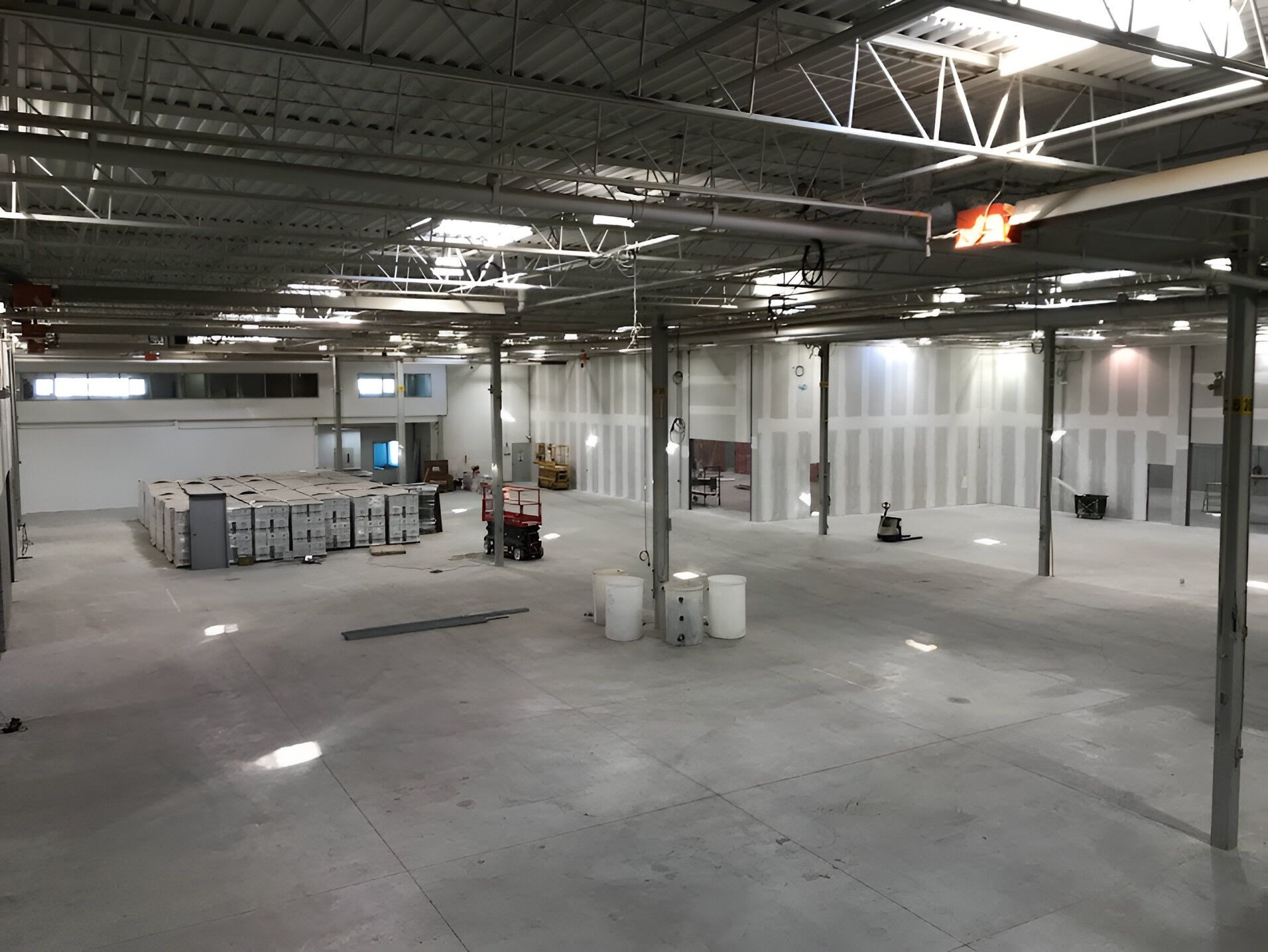 A large empty warehouse with a lot of boxes on the floor.