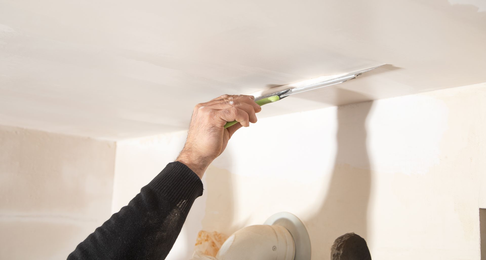 A person is painting a ceiling with a brush.