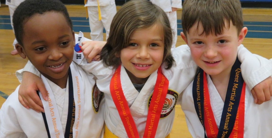 three young children wearing medals are posing for a picture .