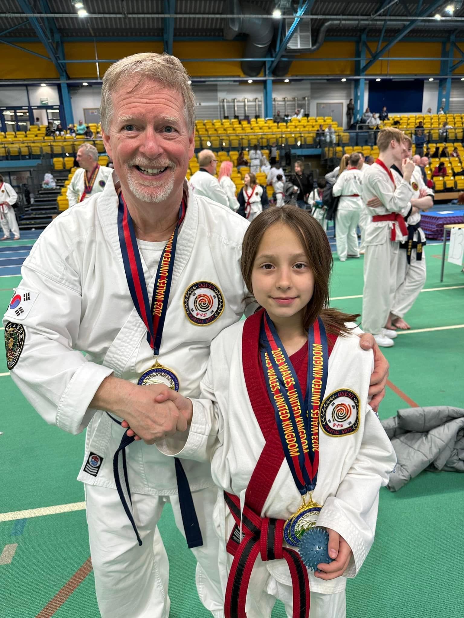 a man and a little girl are posing for a picture in a gym .