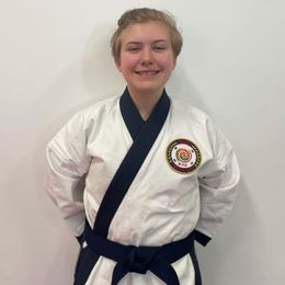 a young man is wearing a karate uniform and smiling .