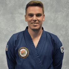 a man in a blue karate uniform is smiling for the camera .