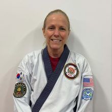 a woman in a karate uniform is smiling for the camera .