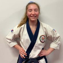 a young woman is wearing a white karate uniform with a blue belt .