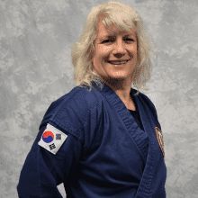 a woman in a blue karate uniform is smiling for the camera .