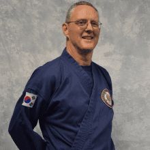 a man in a blue karate uniform is smiling for the camera .