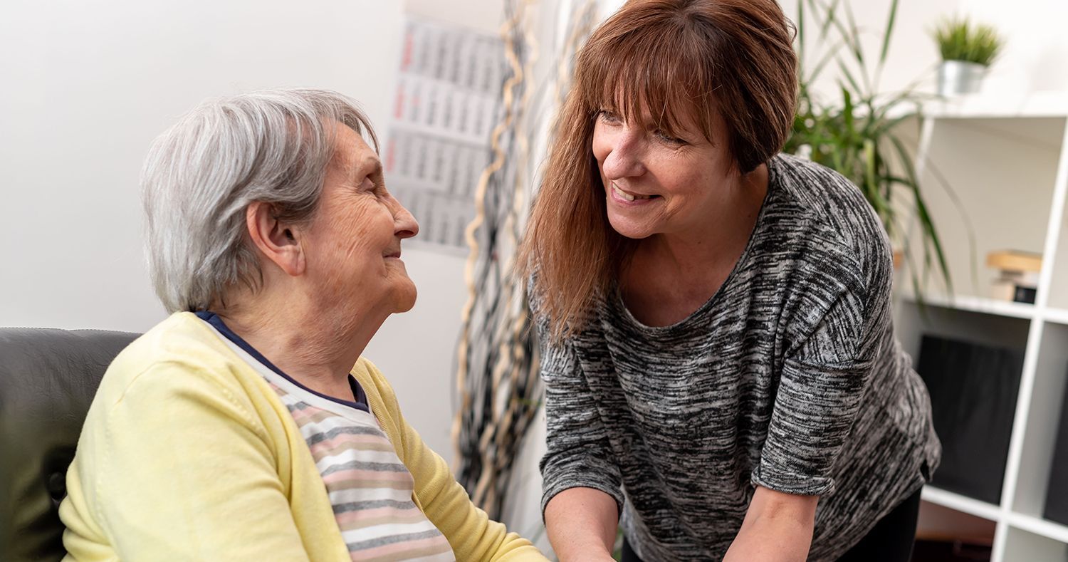 Two women smiling and talking in a bright living room