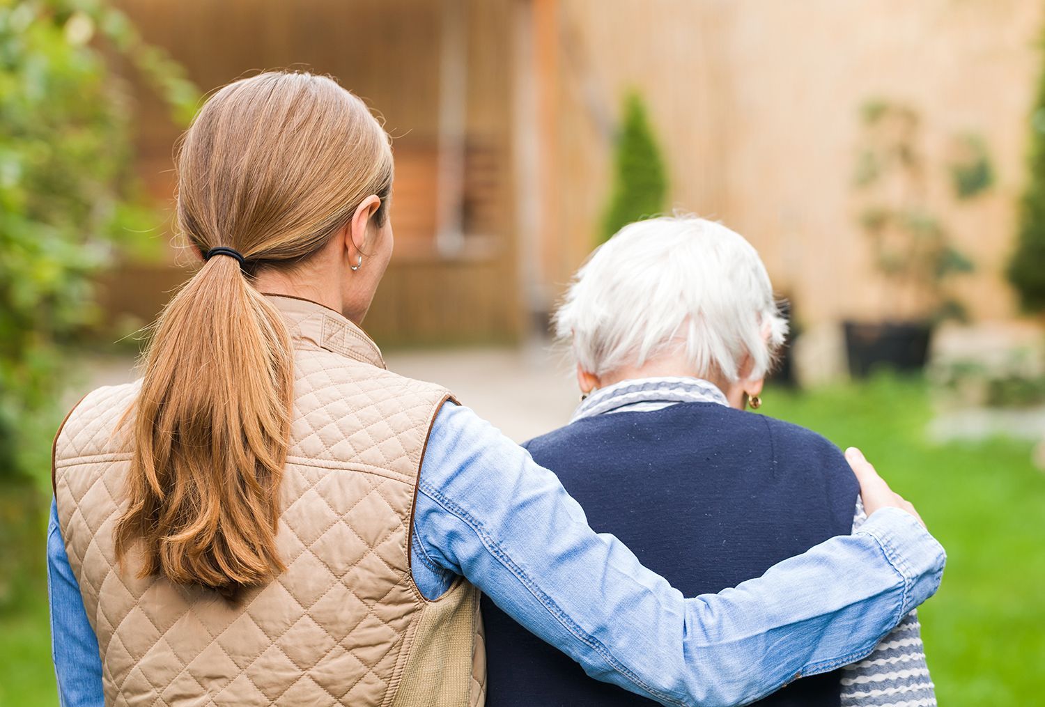 Two people walking outdoors, one with an arm around the other in a supportive gesture.
