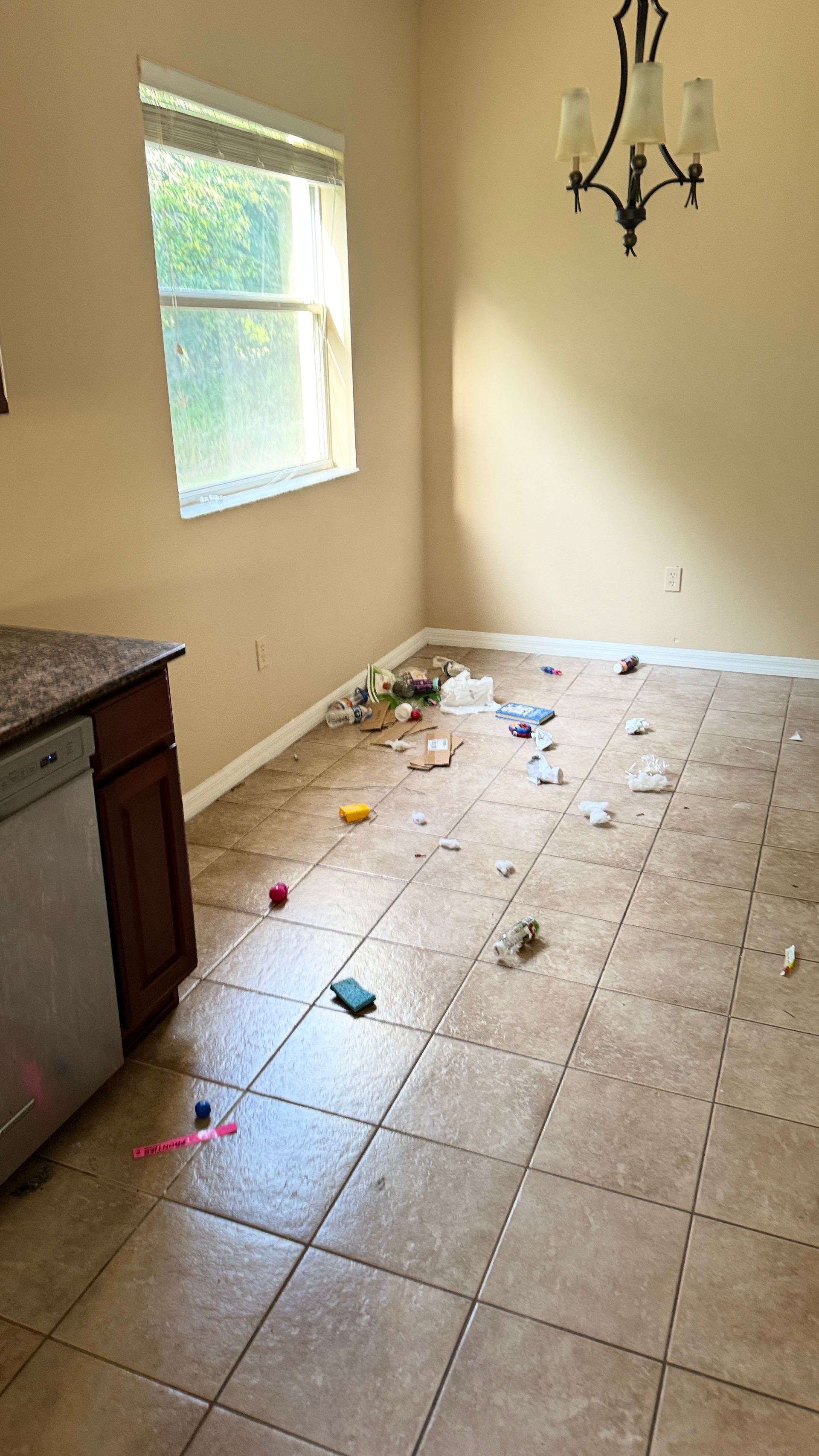 A dining room with a messy floor and a window.