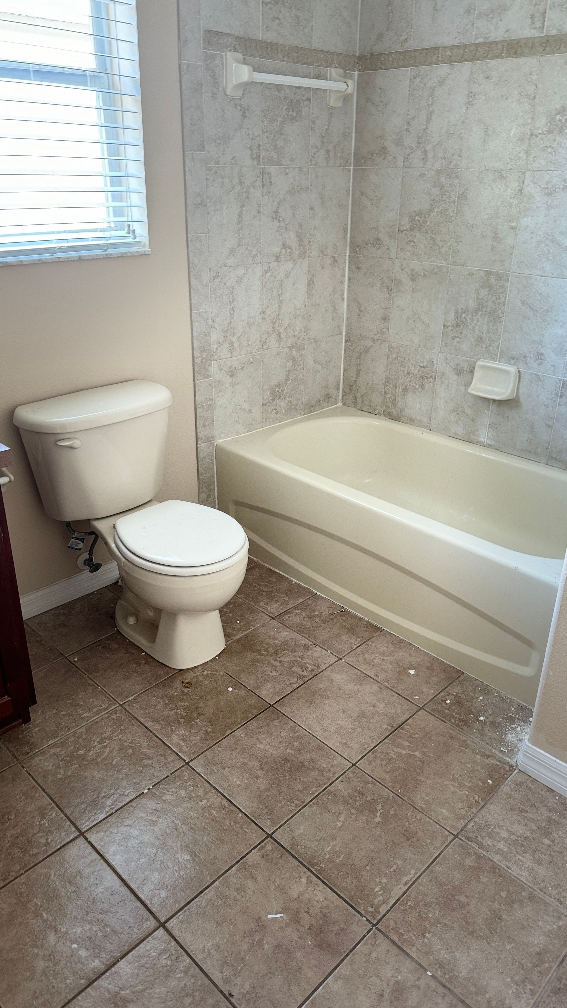 A bathroom with a toilet , bathtub and window.
