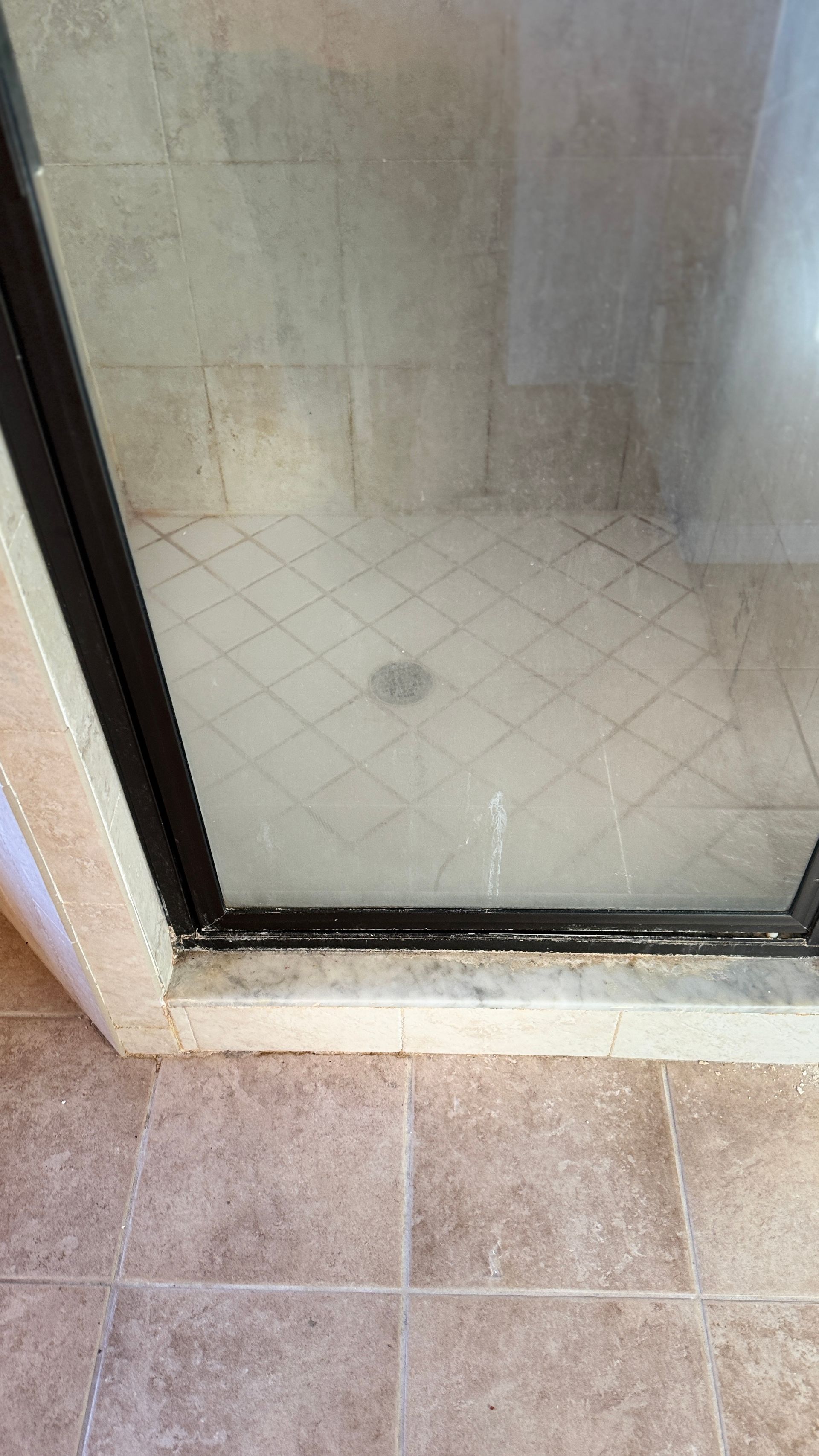 A shower stall with a tiled floor and a glass door.