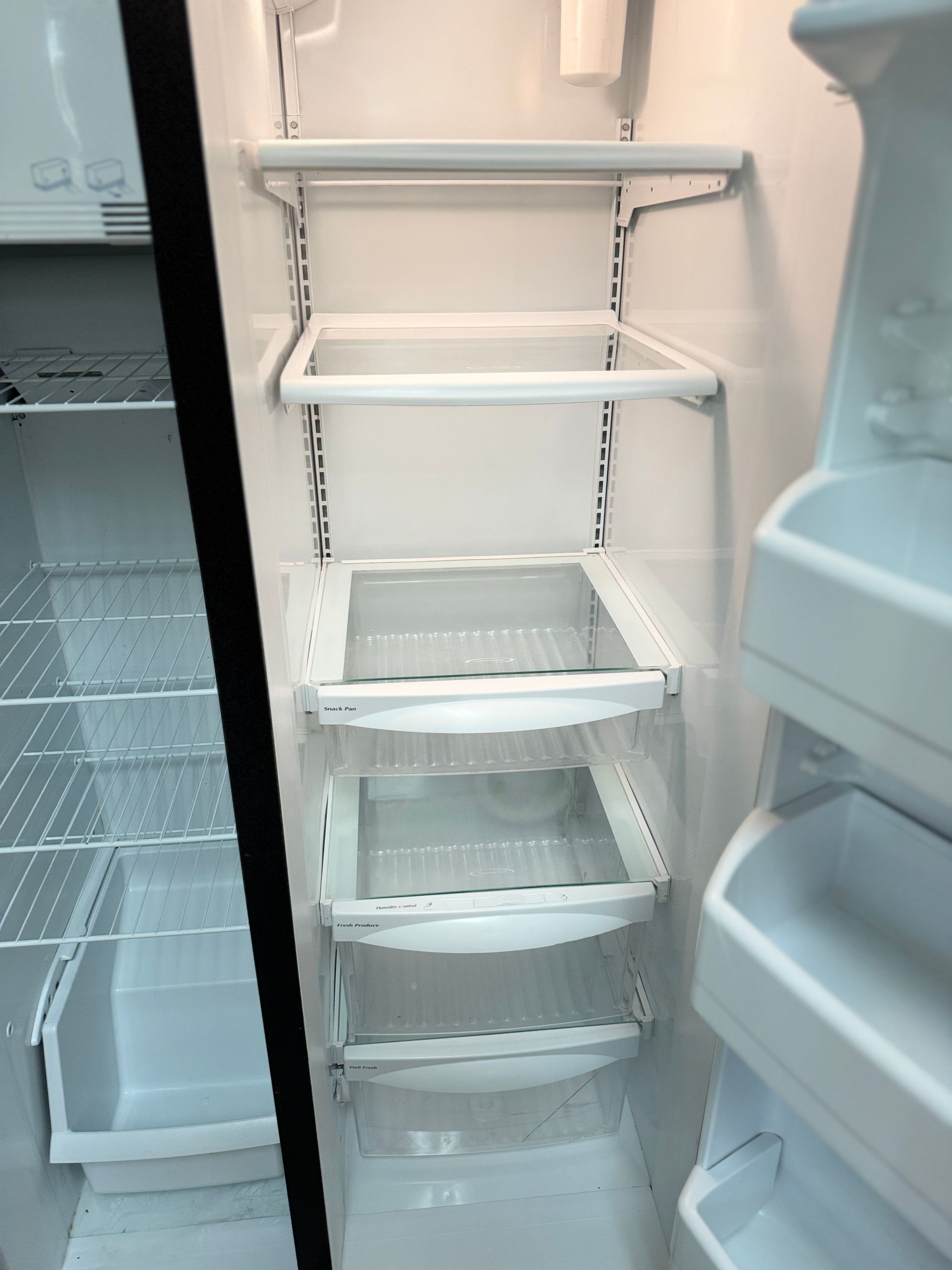 The inside of an empty refrigerator with shelves and drawers