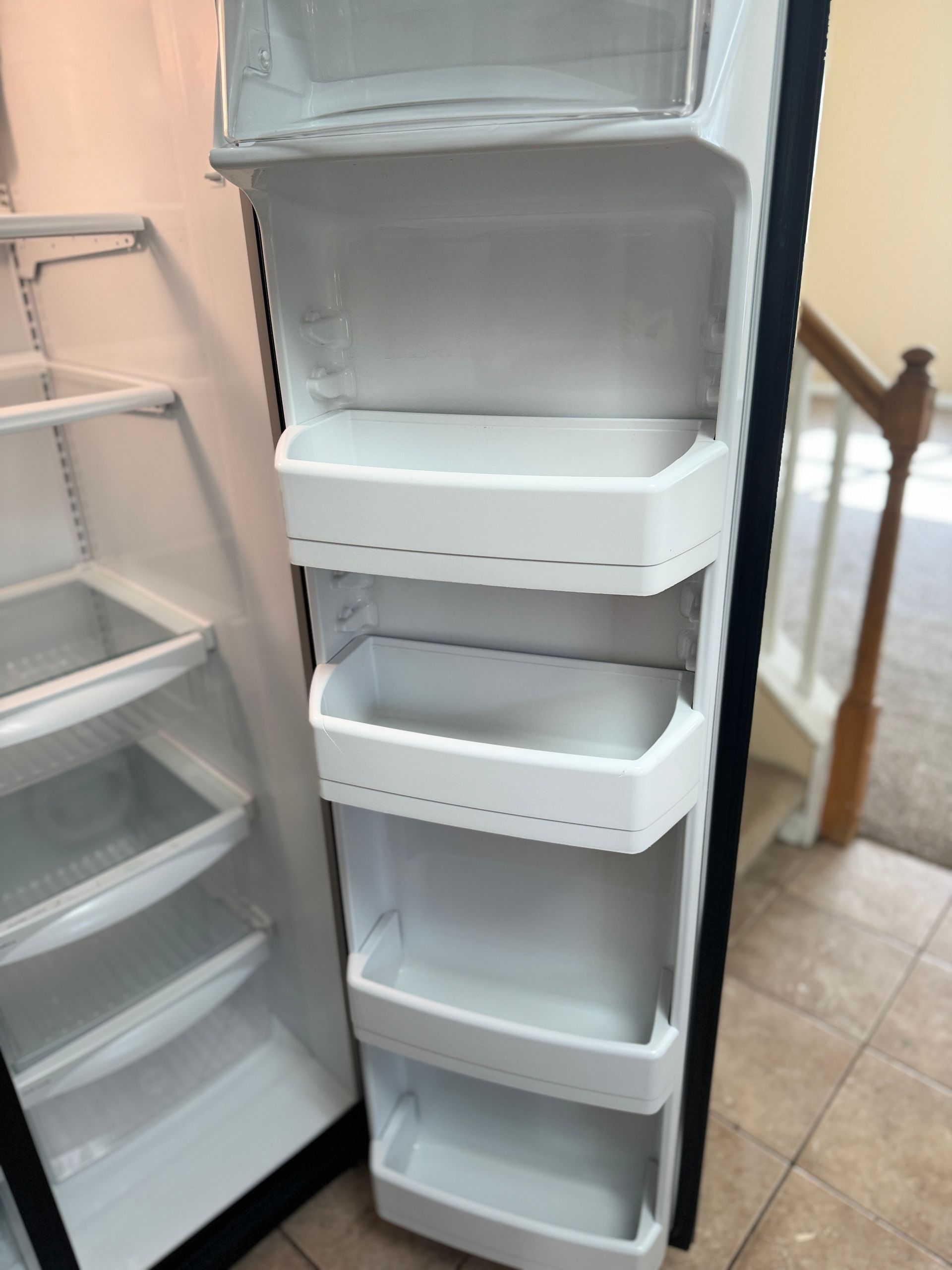 An empty refrigerator with a staircase in the background