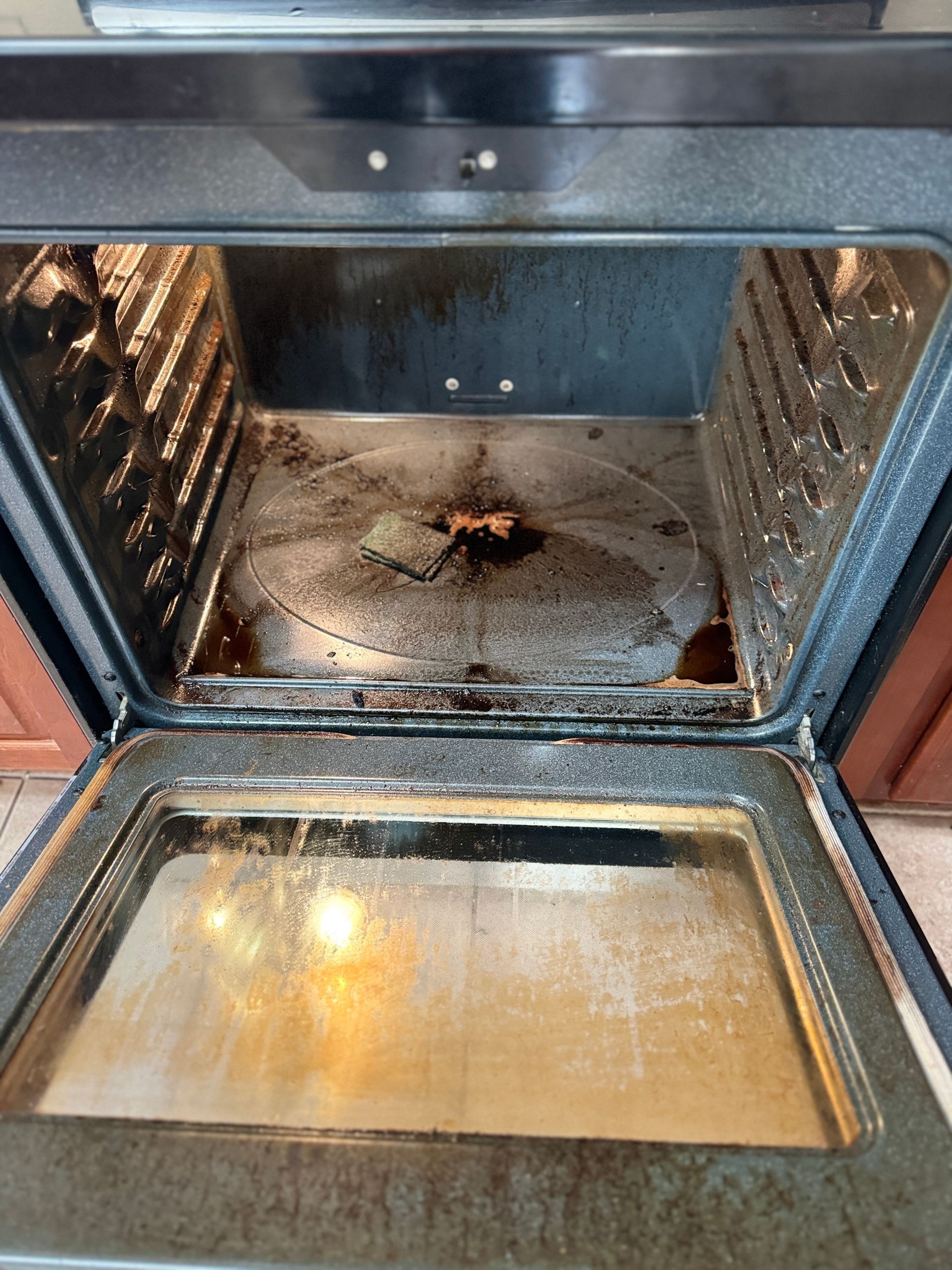 The inside of a dirty oven with the door open.