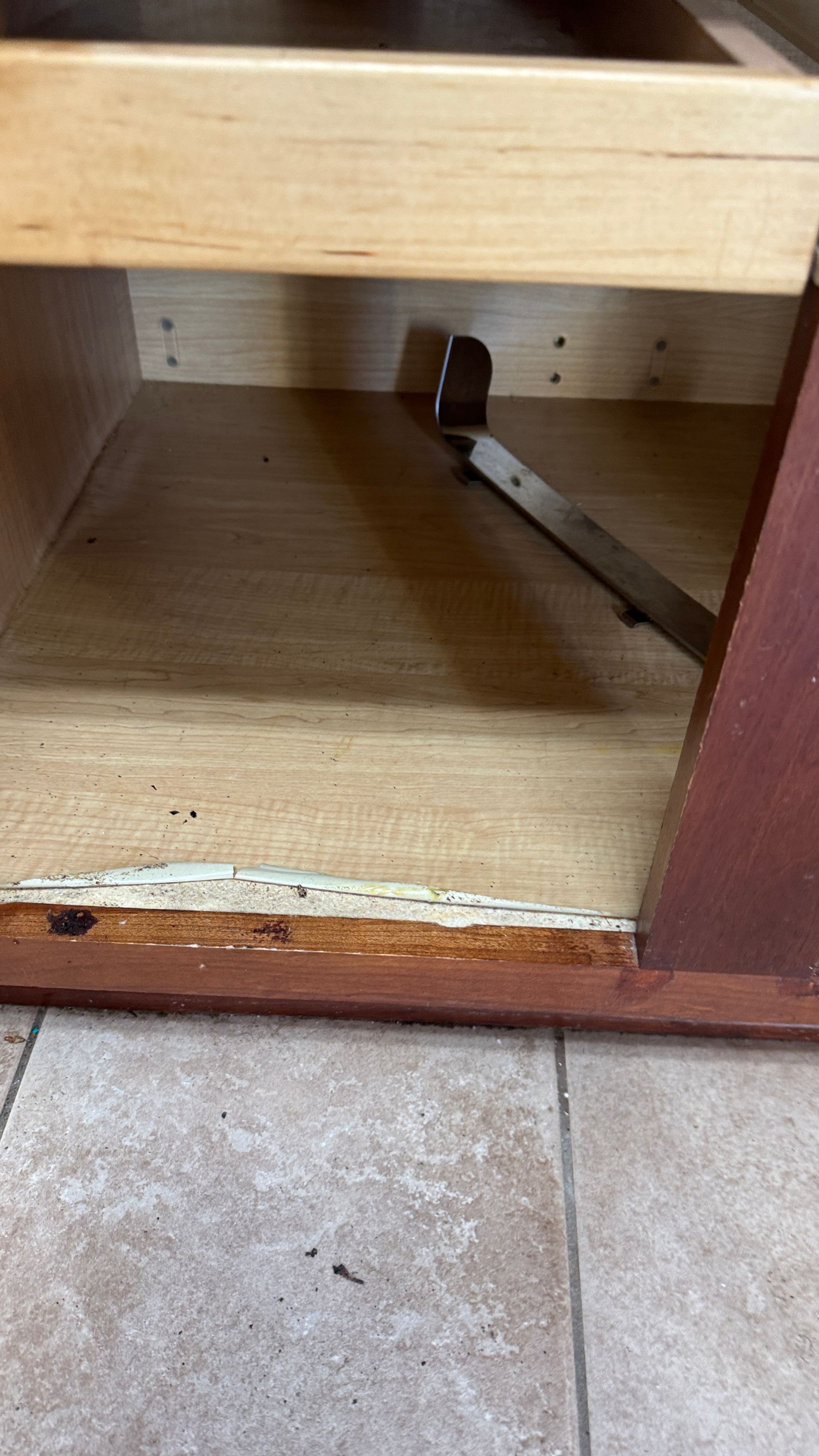 A close up of a wooden cabinet with a metal handle on the floor.