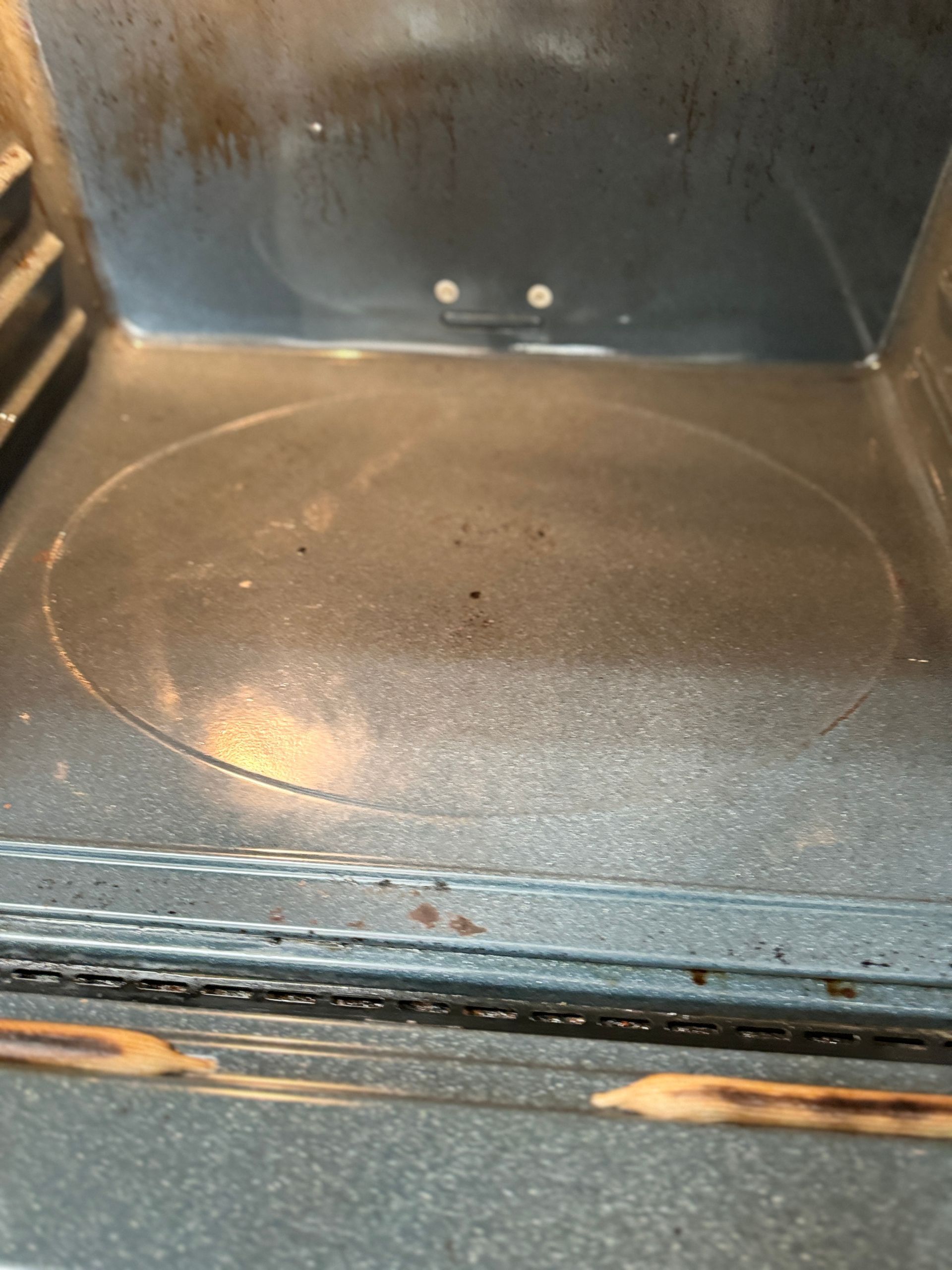The inside of a microwave oven with a dirty glass plate