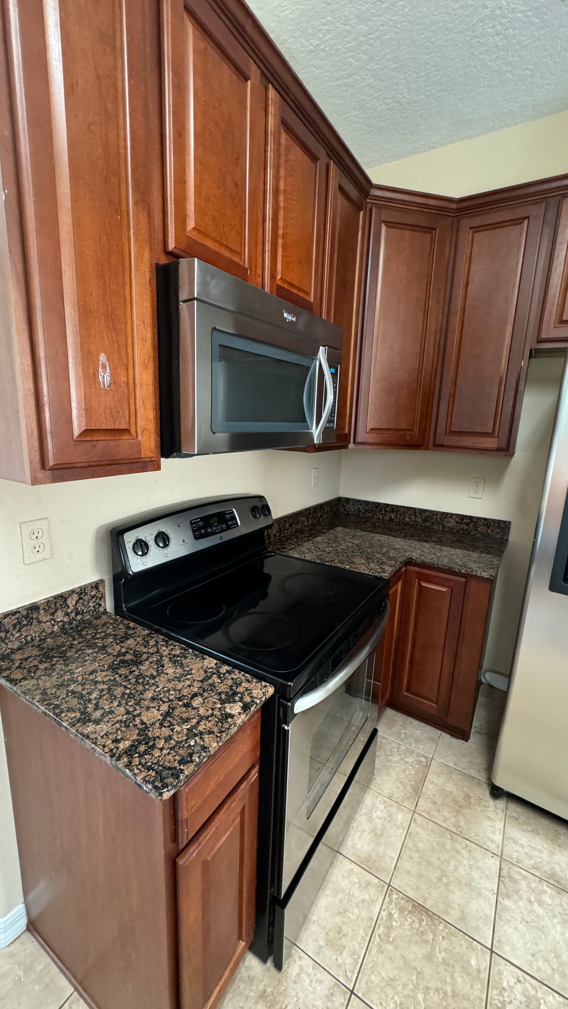 A kitchen with a stove , microwave , and granite counter tops.
