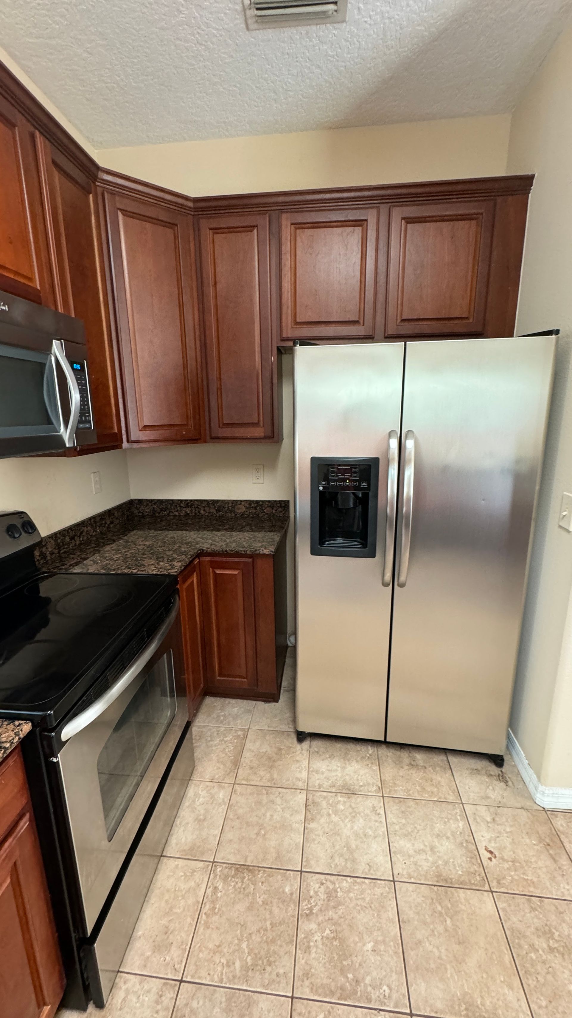 A kitchen with stainless steel appliances and wooden cabinets.