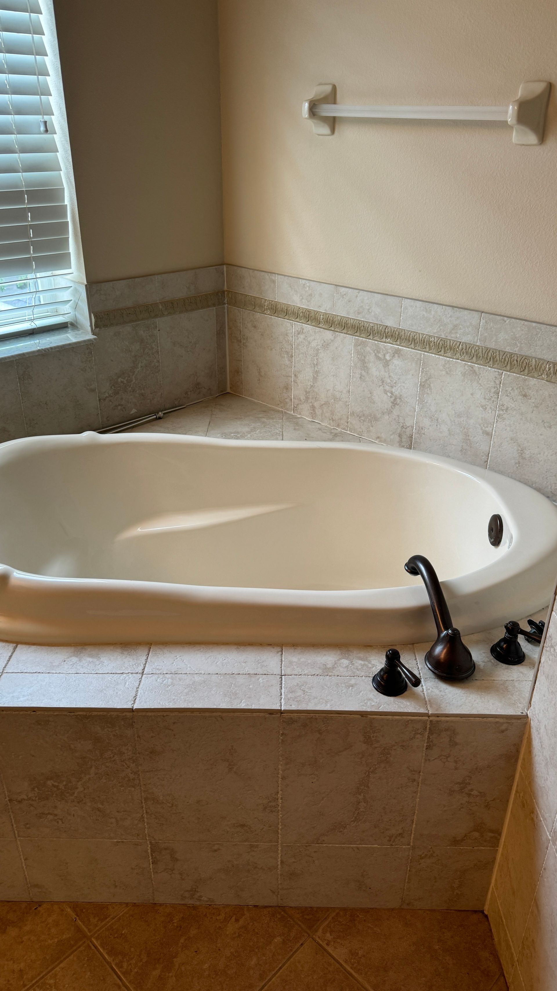 A bathtub in a bathroom next to a window.