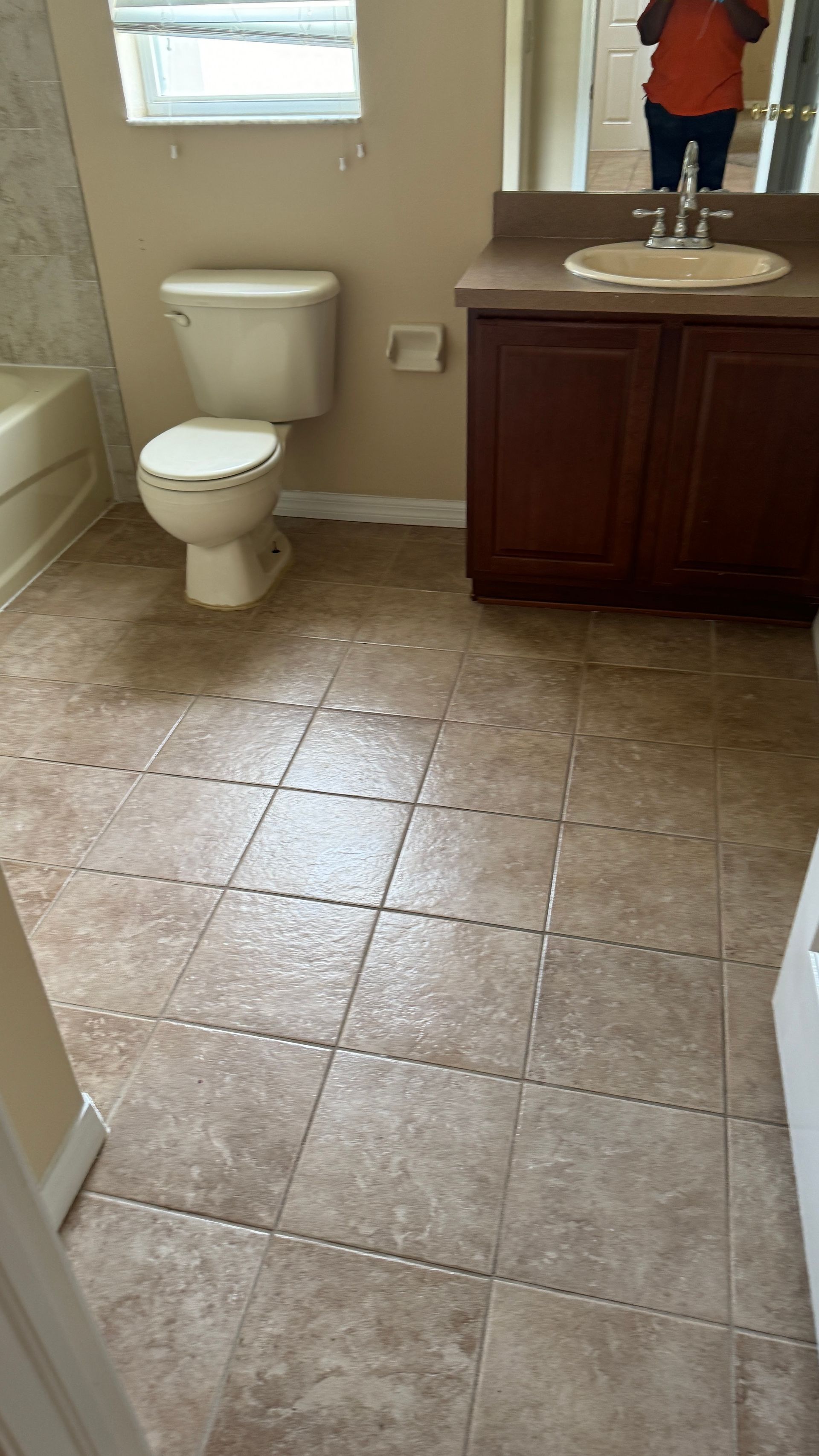 A bathroom with a toilet , sink , and mirror.