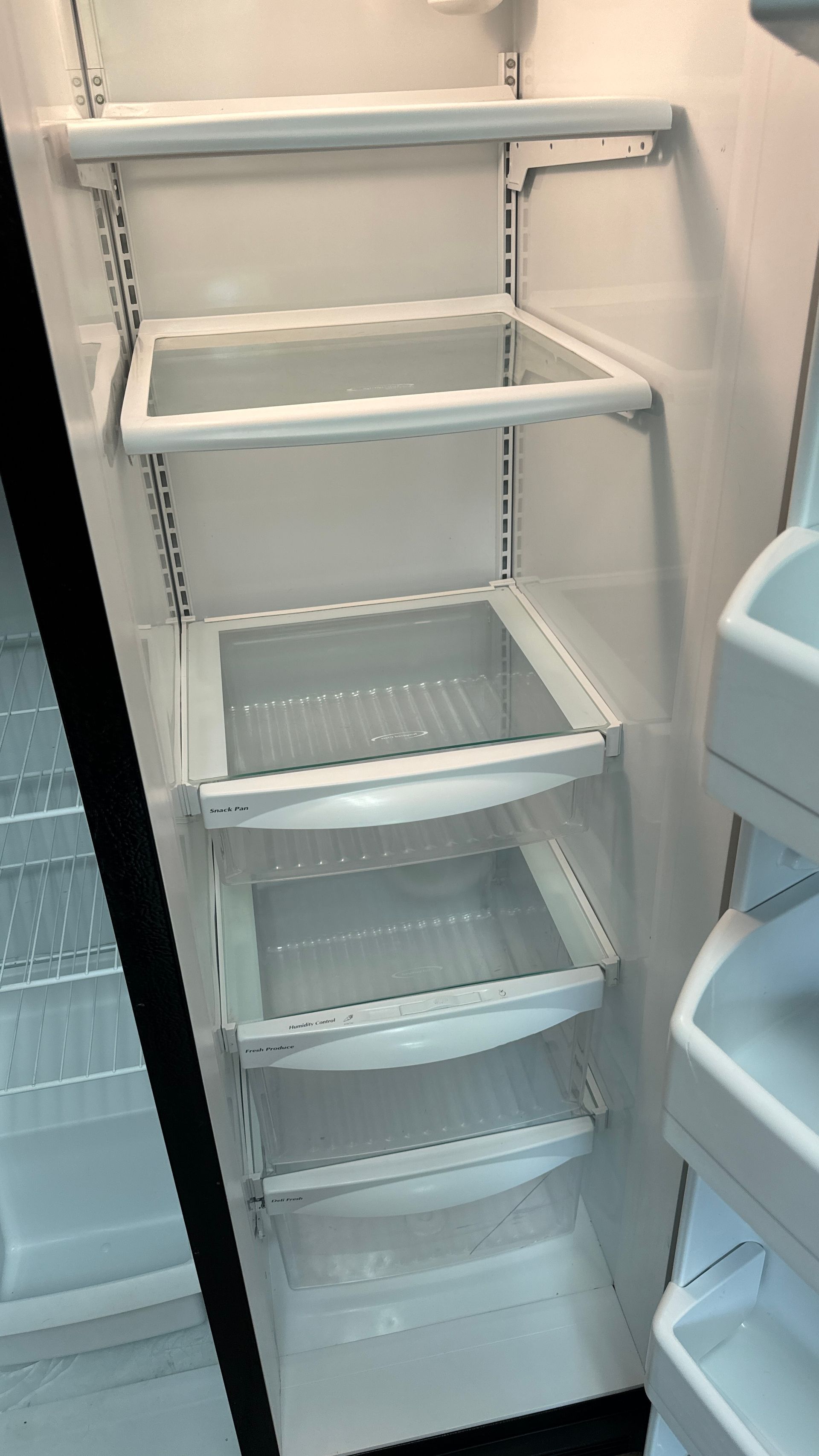 The inside of an empty refrigerator with shelves and drawers.