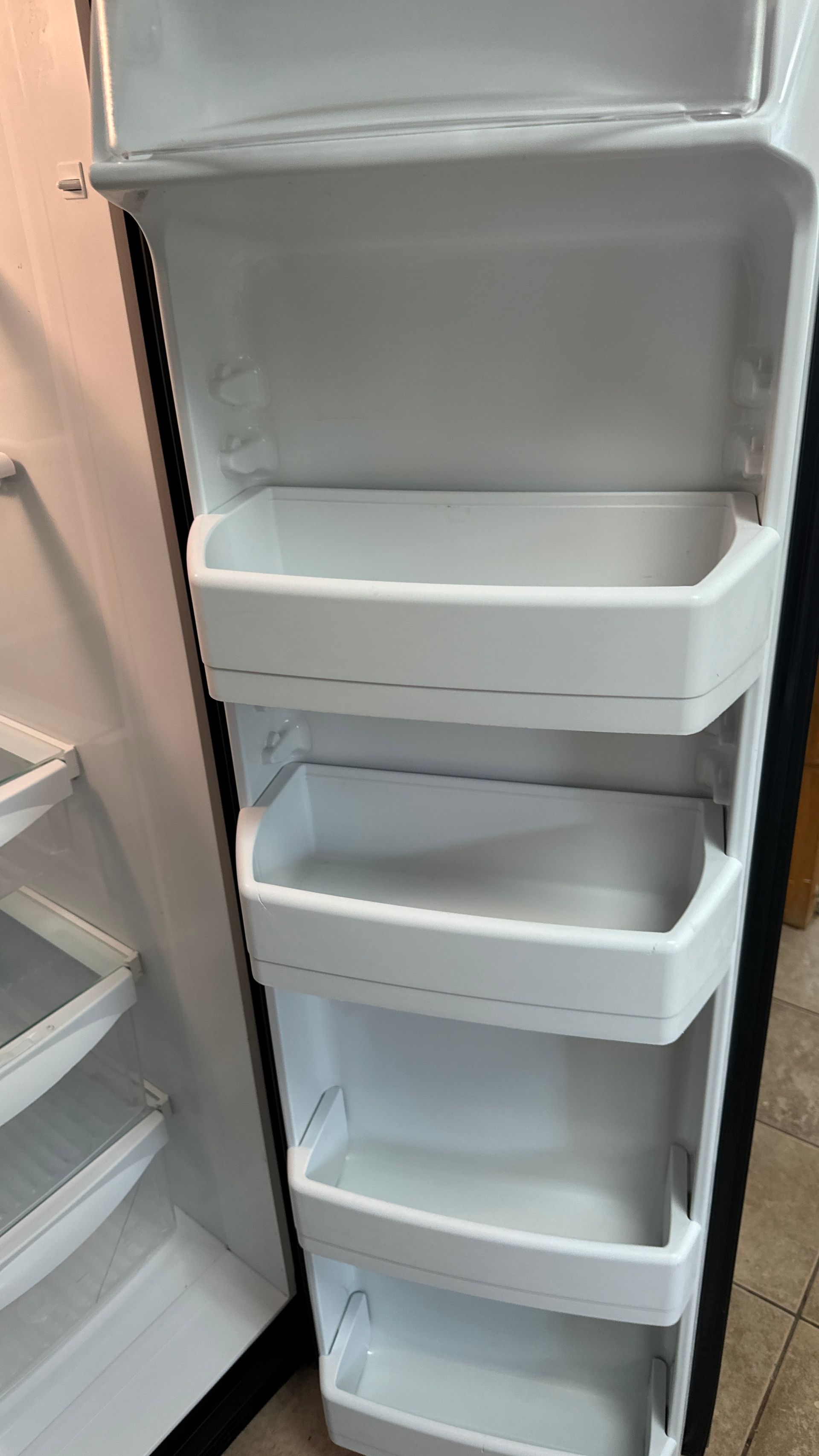 A refrigerator with the door open and empty shelves.