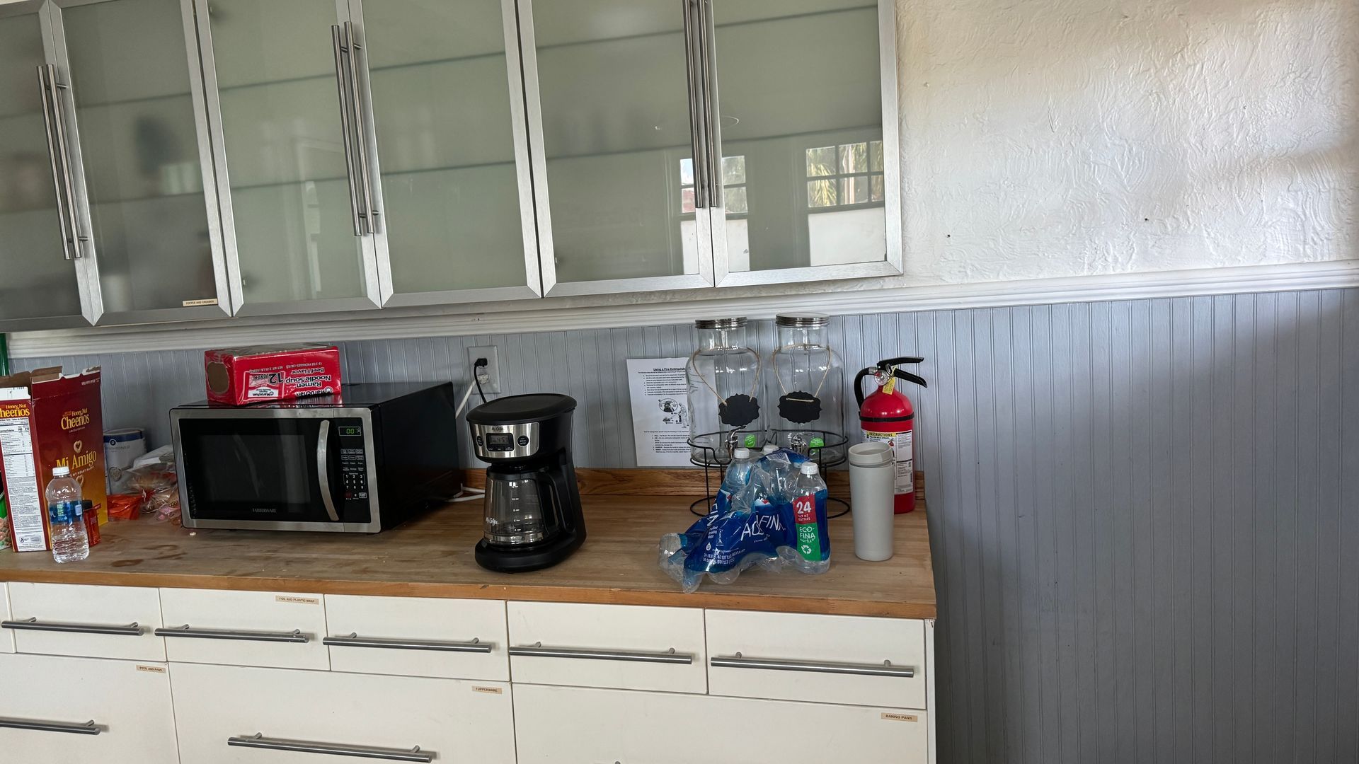 A kitchen with a microwave a coffee maker and a fire extinguisher
