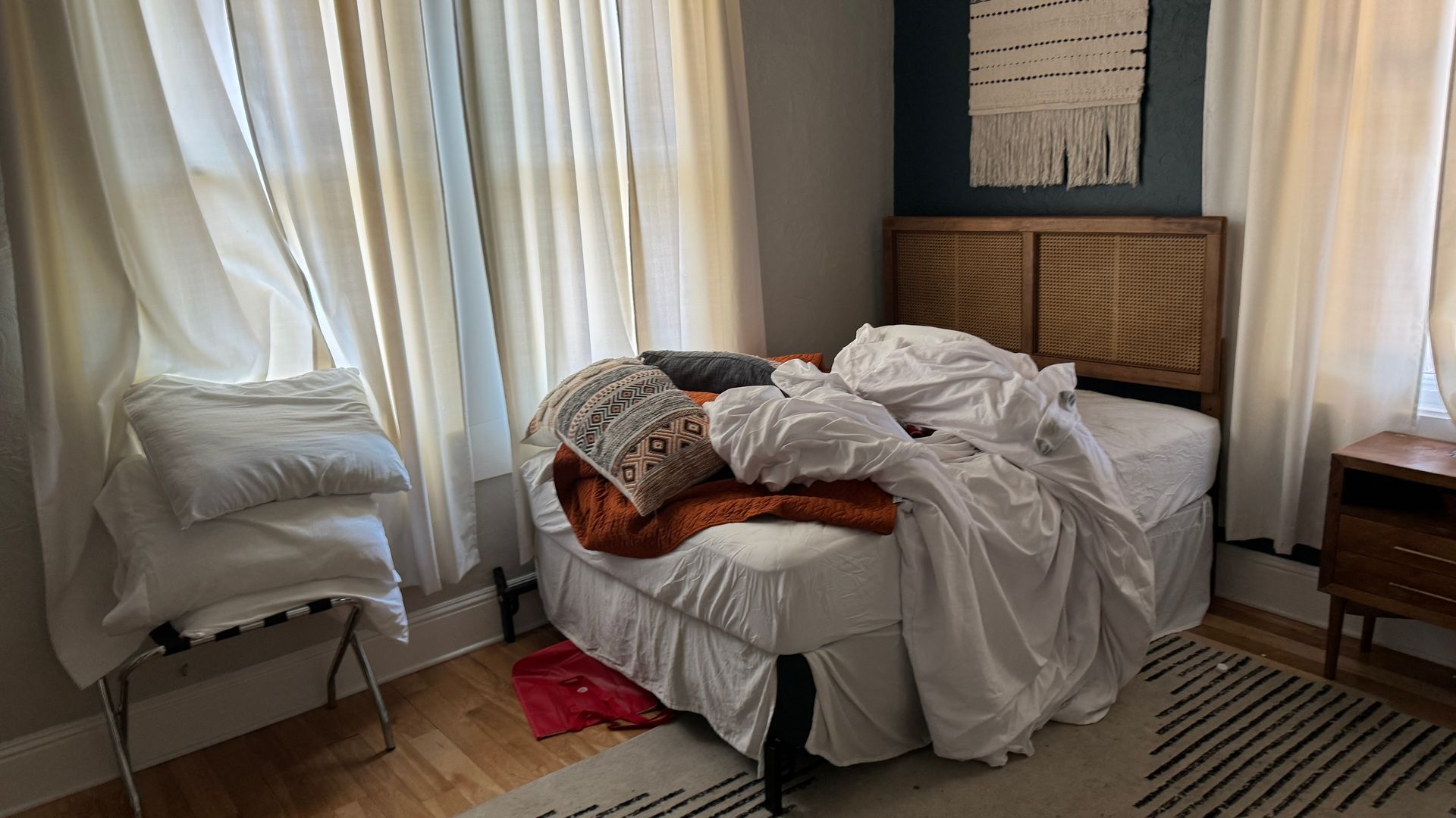 A bed with white sheets and pillows is sitting in a bedroom next to a window.