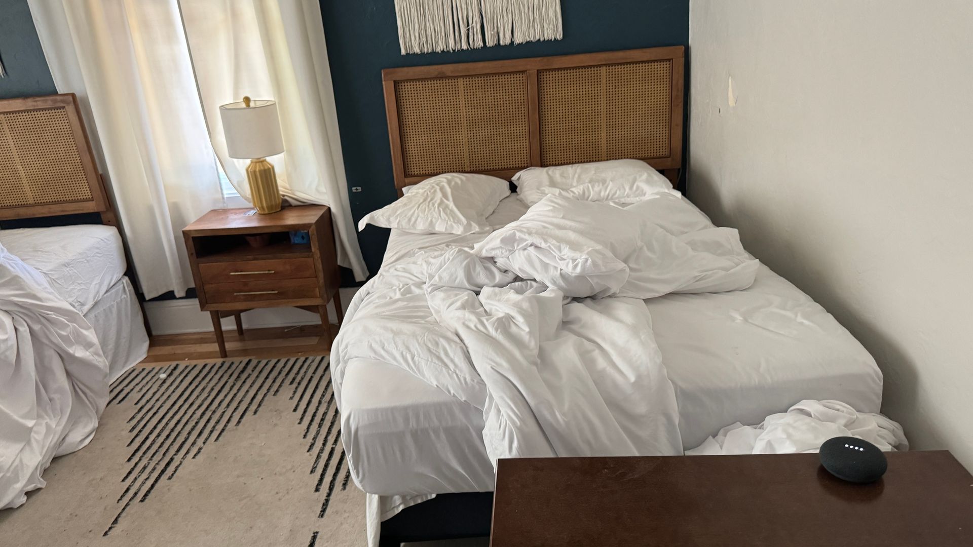 A bedroom with two beds , a nightstand and a lamp.