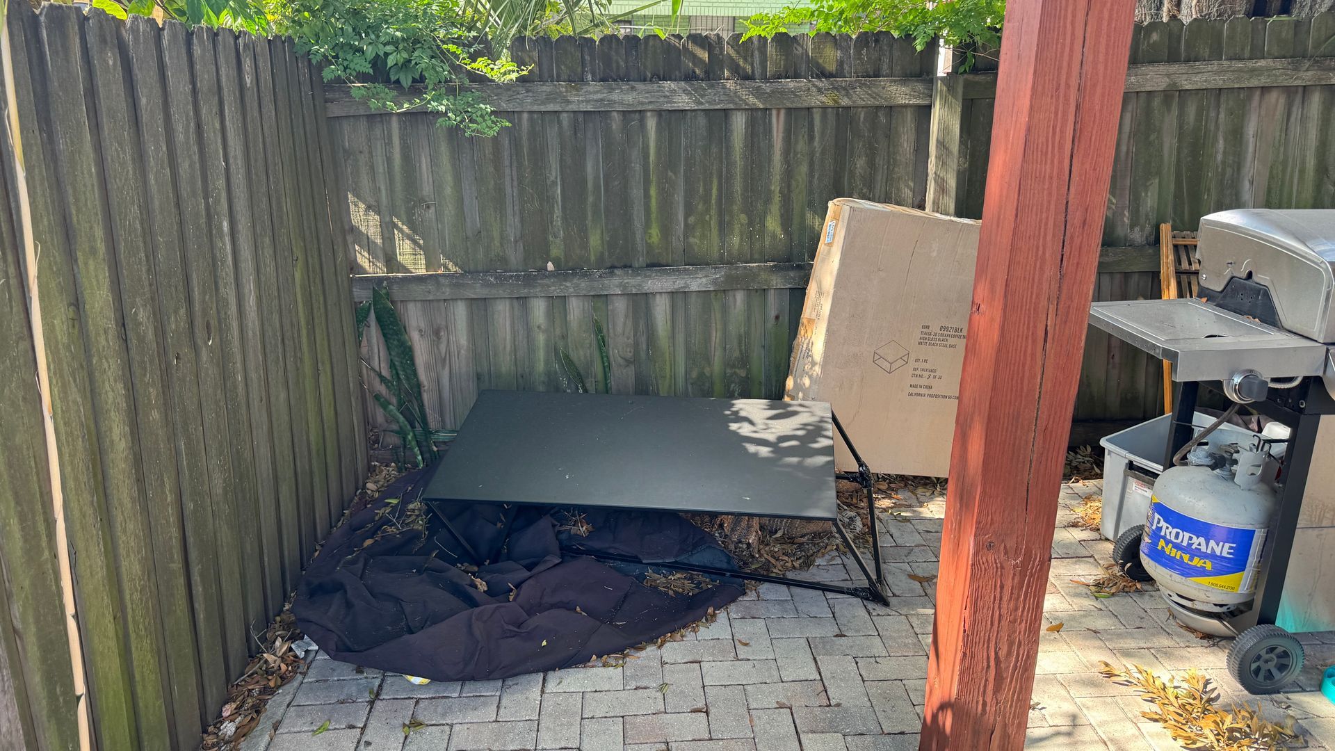 There is a table and a grill in the backyard.