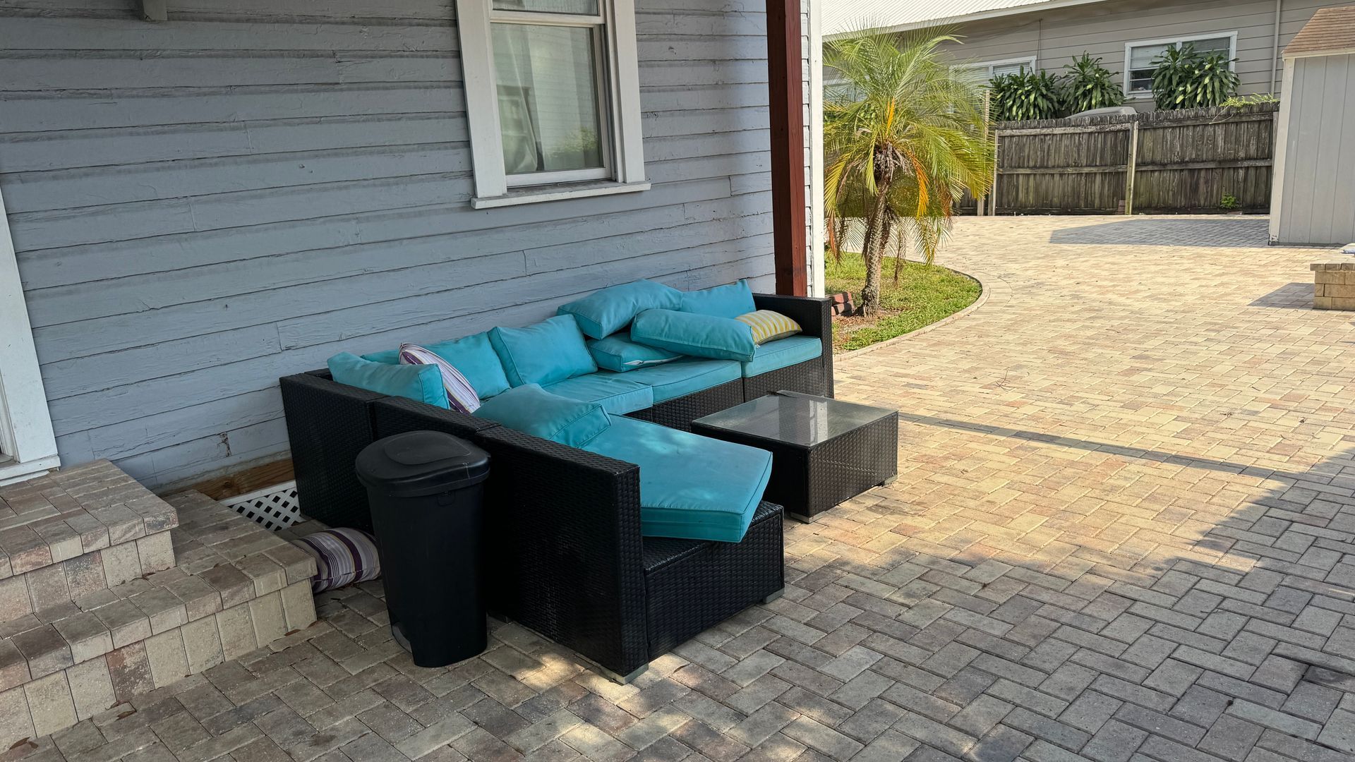 A patio with a couch and a table in front of a house.