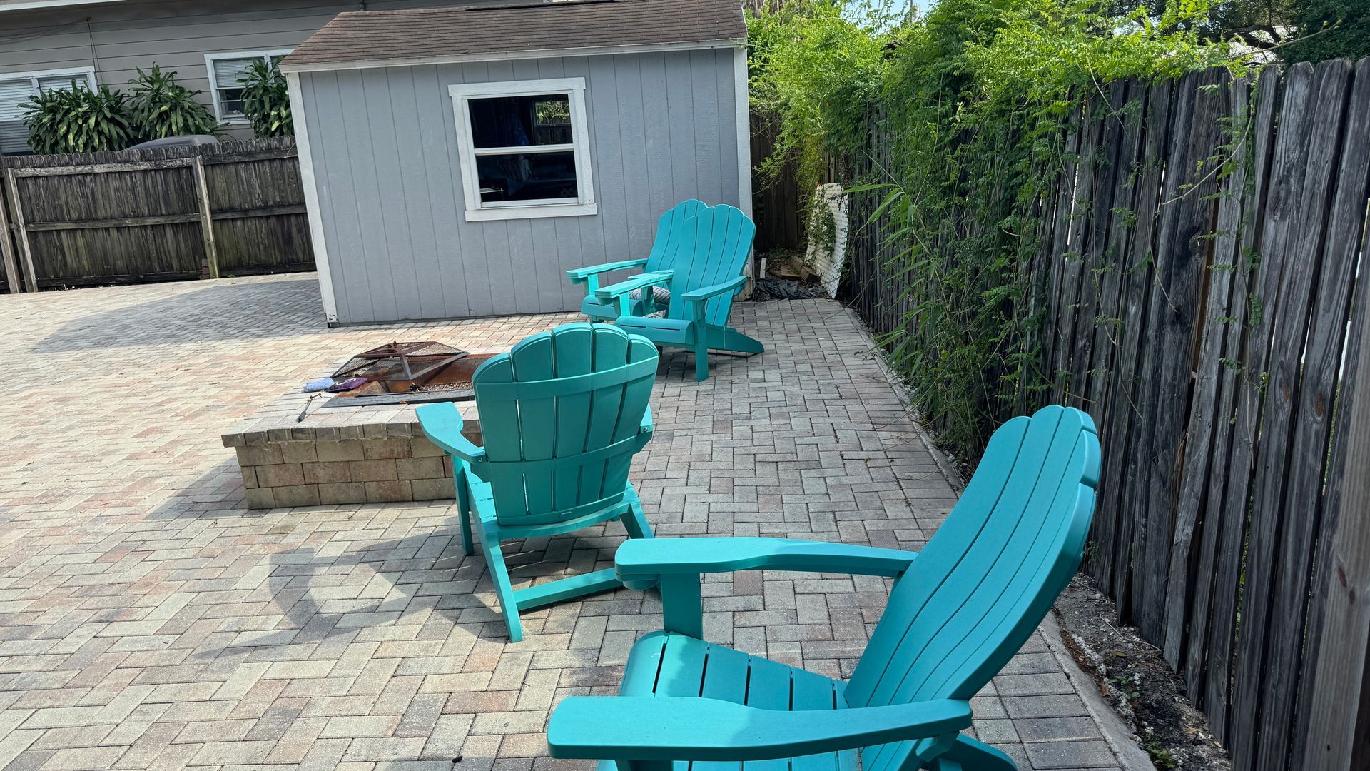A group of blue chairs are sitting on a patio next to a fire pit.