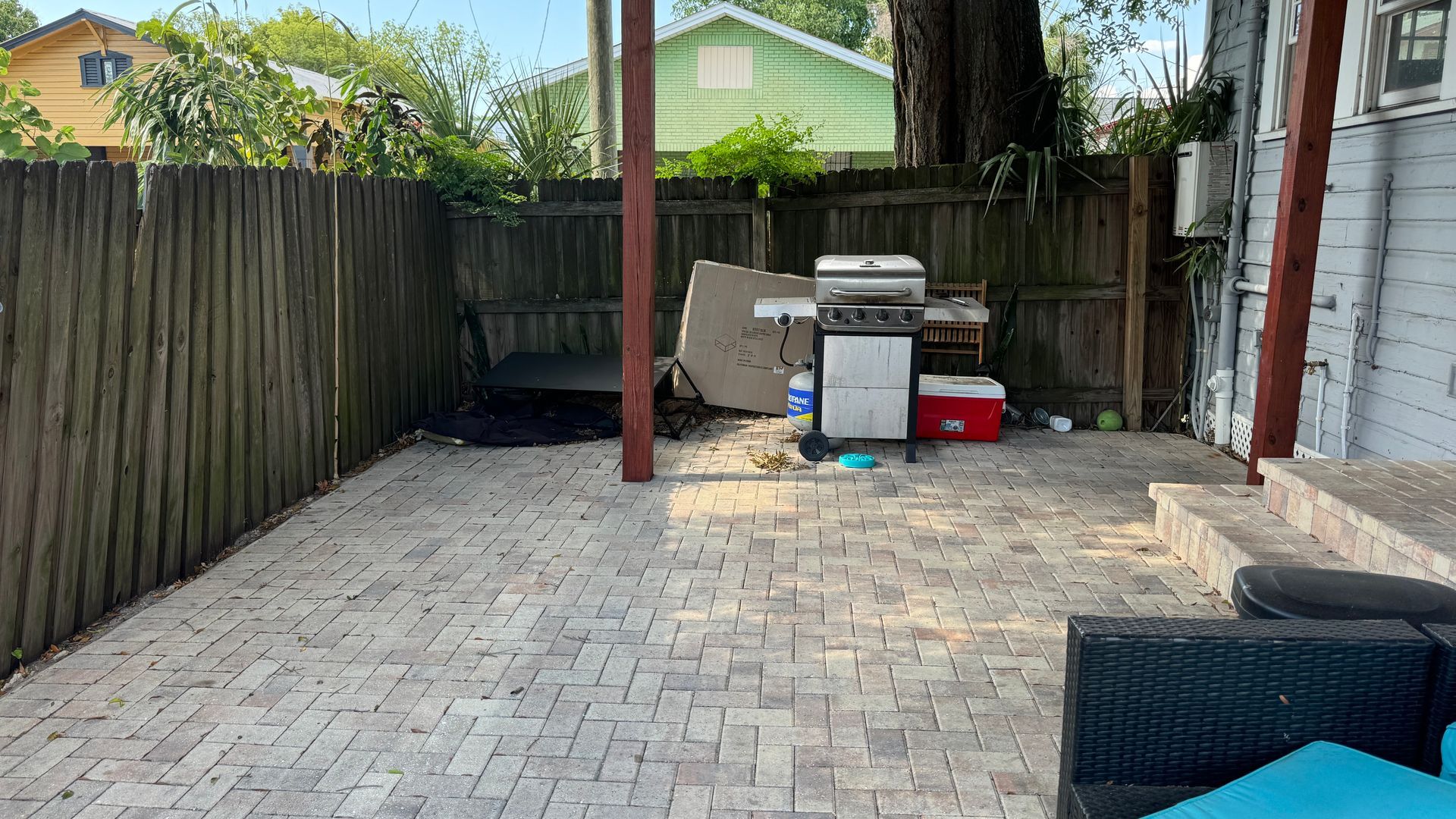 A patio with a grill and a couch in the backyard of a house.